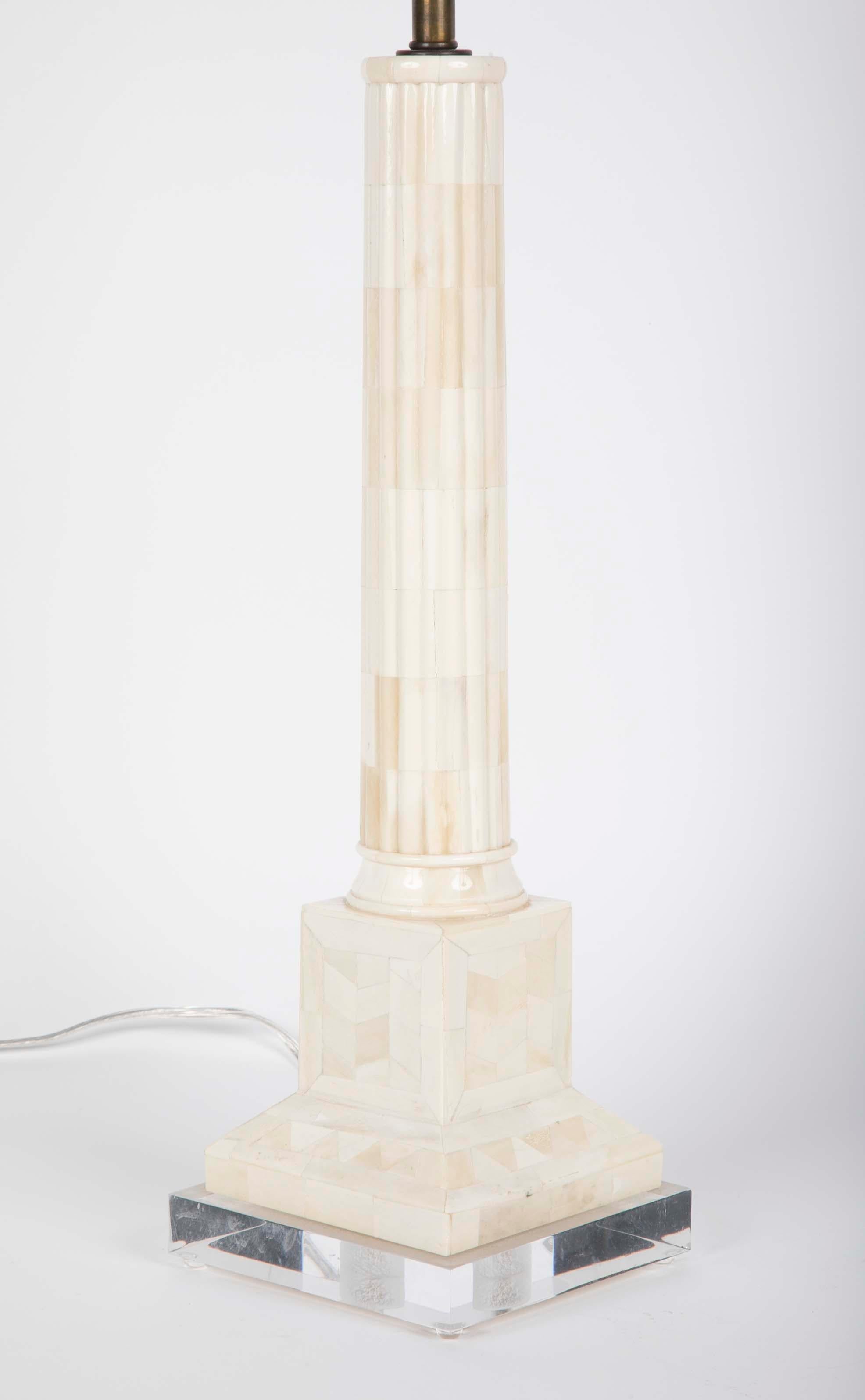 An elegant pair of column-form tessellated and polished bone table lamps. Modeled after Roman marble columns, these lamps are the perfect modern expression of the neoclassical. The round shafts resting on square plinths supported by Lucite bases.