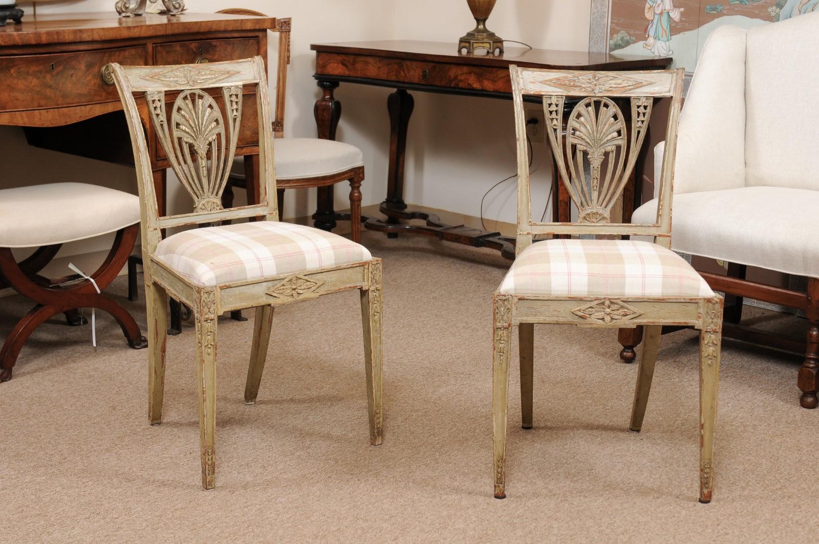 The pair of painted pale green Swedish side chairs with carved back spats, slip in plaid linen upholstered seats, carved frieze and tapered legs below.