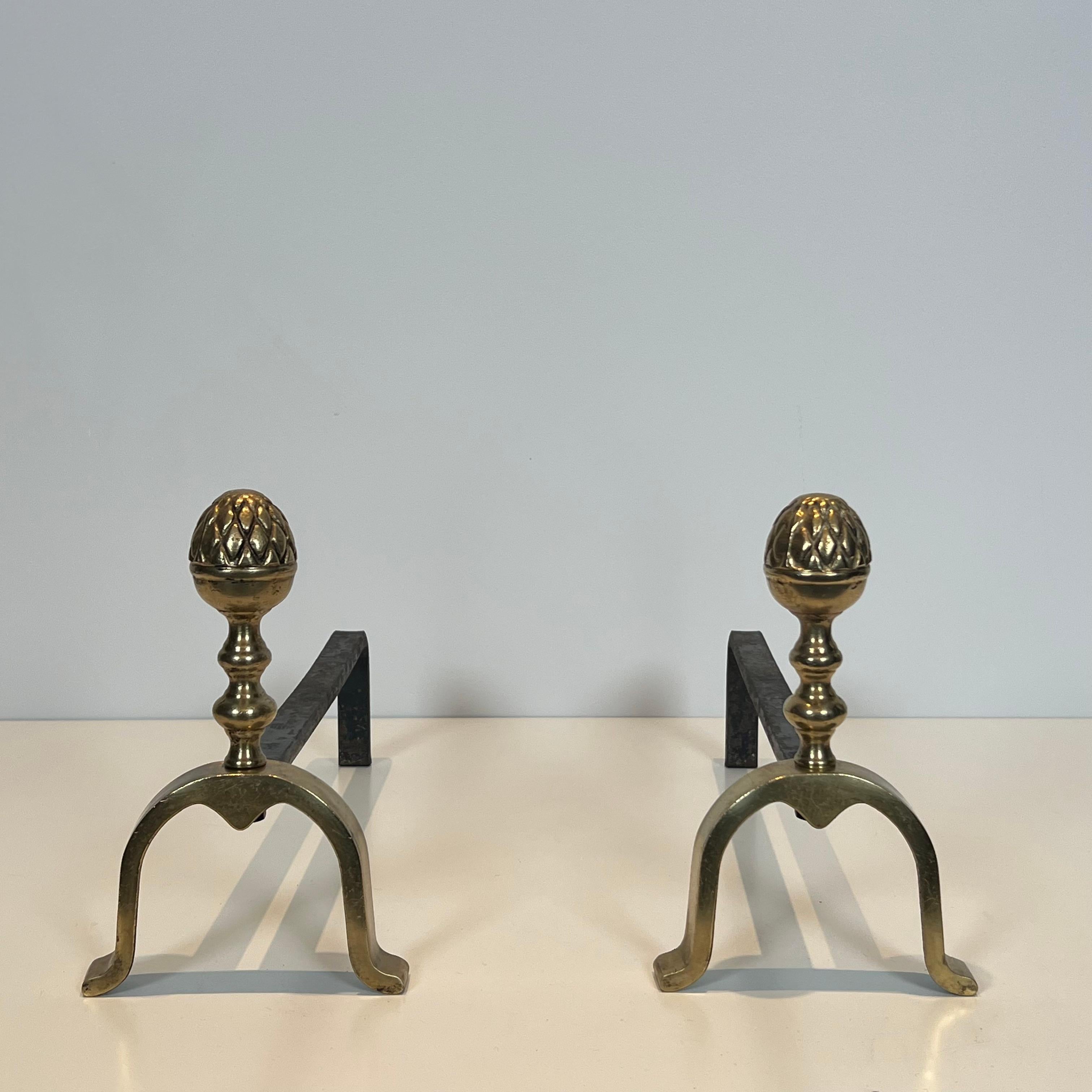 Este par de morillos de piñas de estilo neoclásico son de latón. Se trata de una obra francesa del estilo de la Maison Jansen. Alrededor de 1940