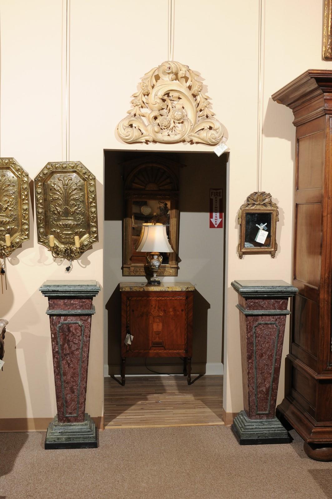 A pair of Neoclassical Style Red & Green Marble Pedestals from 19th Century Italy. Unusual Red Marble is featured in the main piece with a Green graduated stepped form base, topper and frame detailing and a black marble bottom.