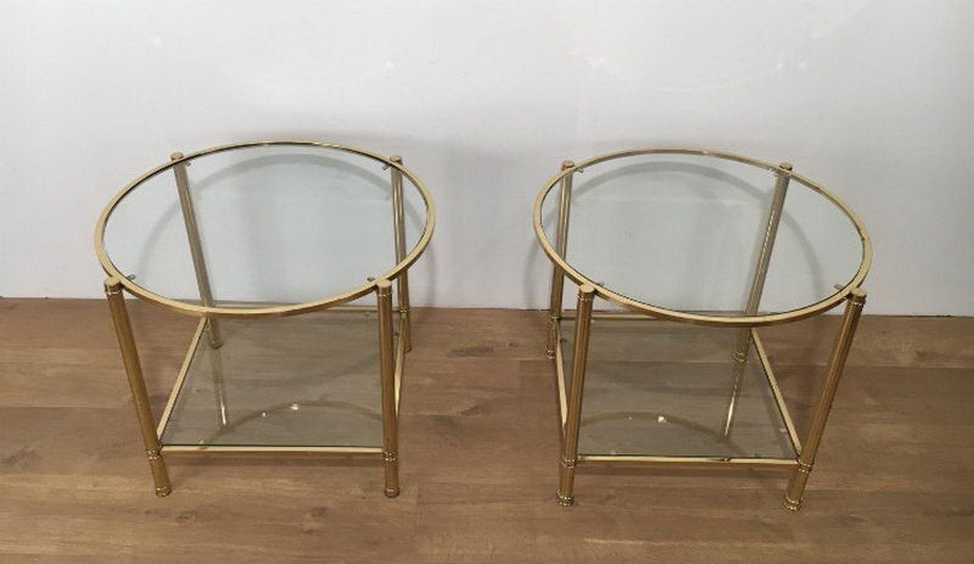 This nice and elegant pair of round side tables is made of brass with two glass shelves, a round glass shelf on top and a square one on the bottom. This is a French work. Circa 1940