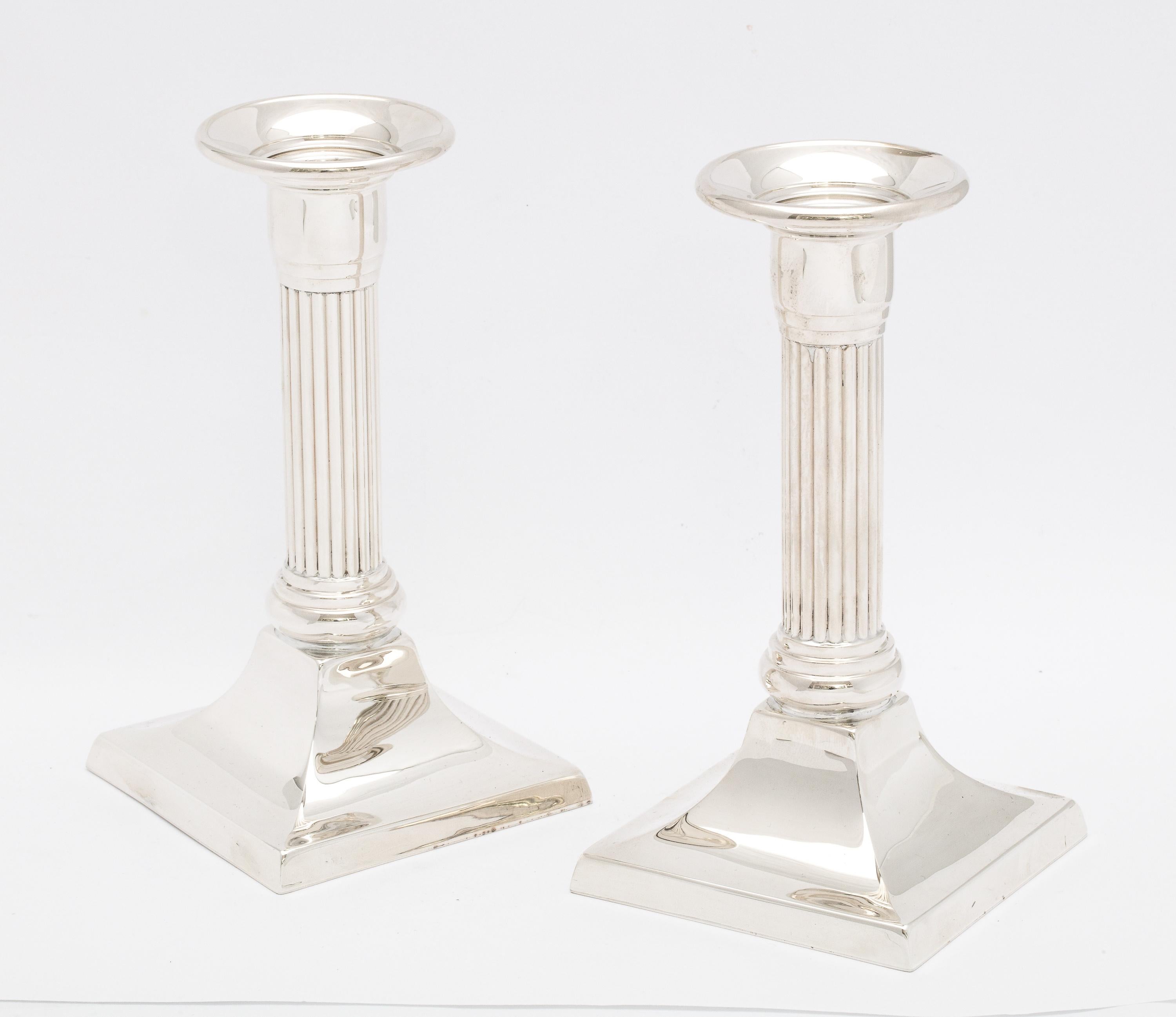 Pair of neoclassical-Style, sterling silver, column-form candlesticks, Empire Silver Company, New York, Ca. 1960's. Each candlestick measures 5 1/2 inches high x 3 inches wide (at widest point) x 3 inches deep (at deepest point). Weighted. Dark