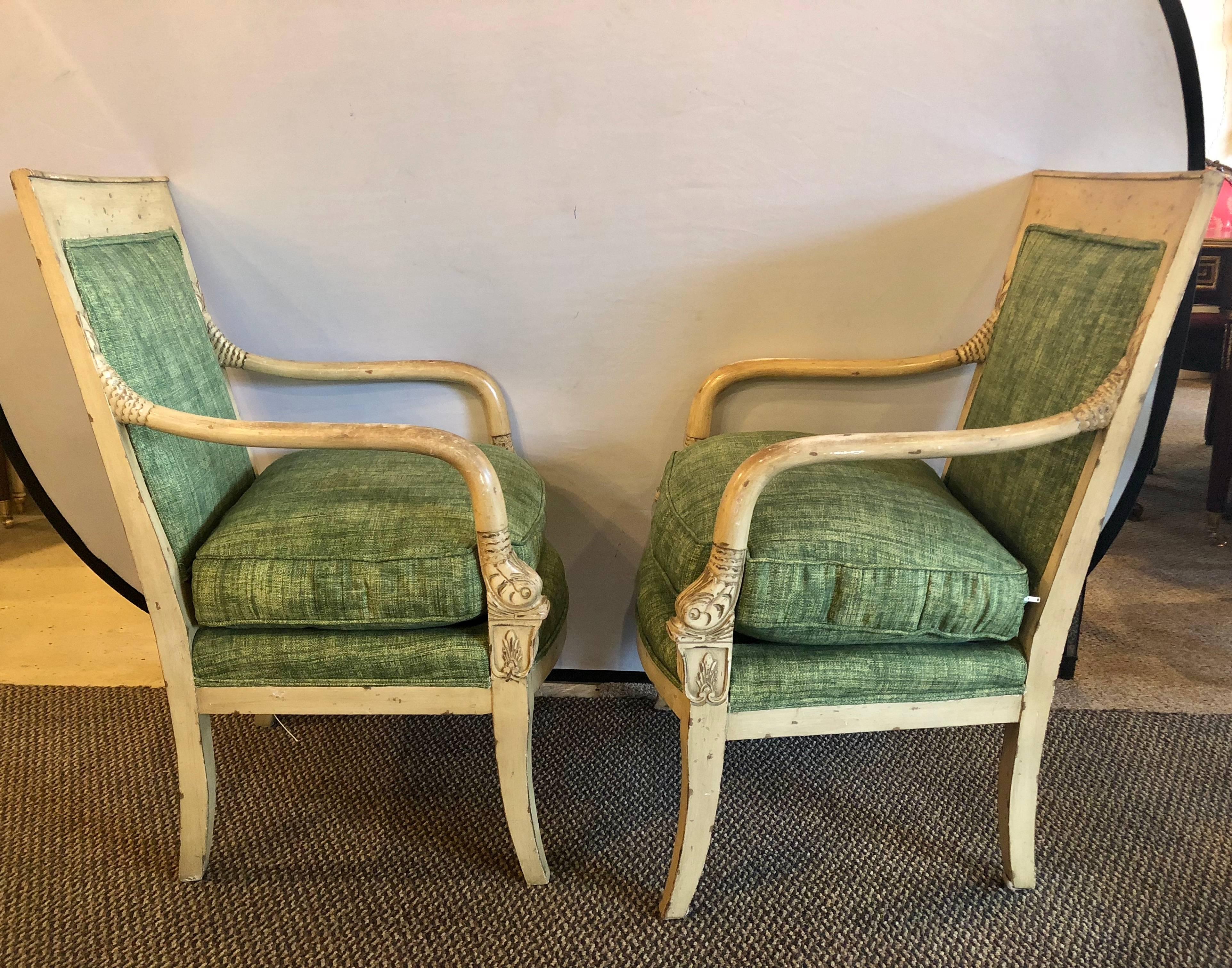 Pair of neoclassical style carved dolphin head distressed Bergeres or armchairs having a new fabric. These purposely distressed arm chairs have fish head hand rests carved into the frames. Each in a forest green material with down cushions. This