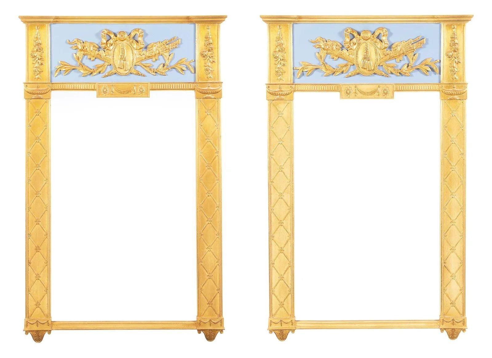 Pair of console, pier or wall mirrors, Hollywood Regency style. 
Fine Carvers Guild pair of mirrors each having a clear center panel flanked by gilt columns leading to a celeste blu and glit carved pediment having a shield and crossed swords.