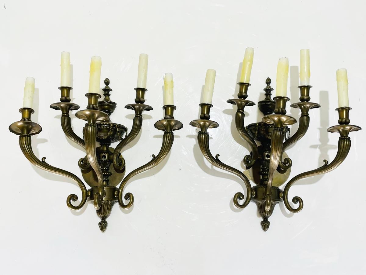 Introducing our exquisite Pair of Neoclassical Style Wall Sconces in Solid Bronze, the perfect addition to any discerning home or business owner's collection. Crafted from high-quality bronze, these wall lights boast an impressive 5 arms, each
