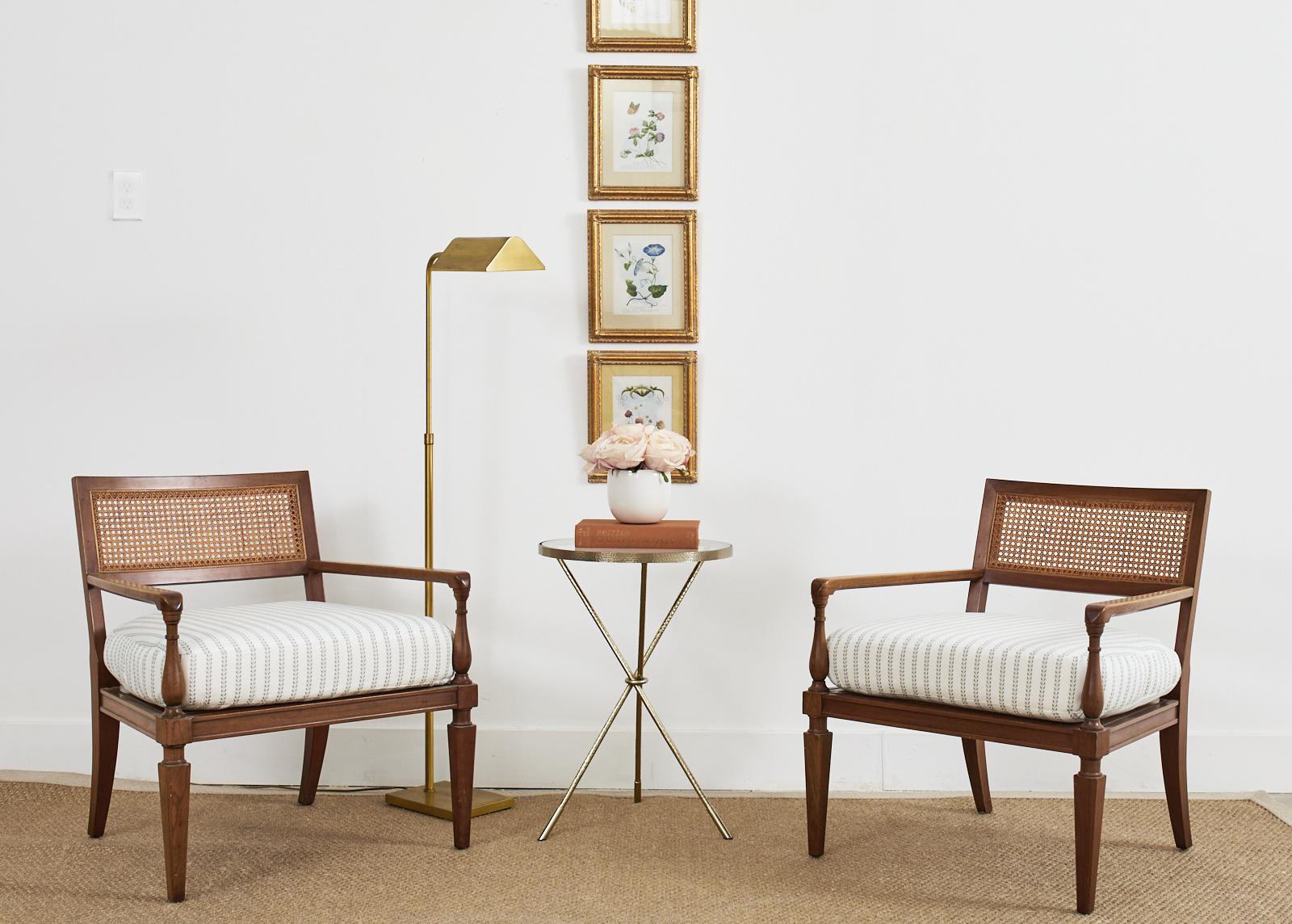 Mid-century modern pair of lounge chairs or armchairs made by Baker. The chairs feature a walnut frame with a generous caned seat and back. Constructed with neoclassical styling cues evoking designs by Michael Taylor. The chairs have a rectangular