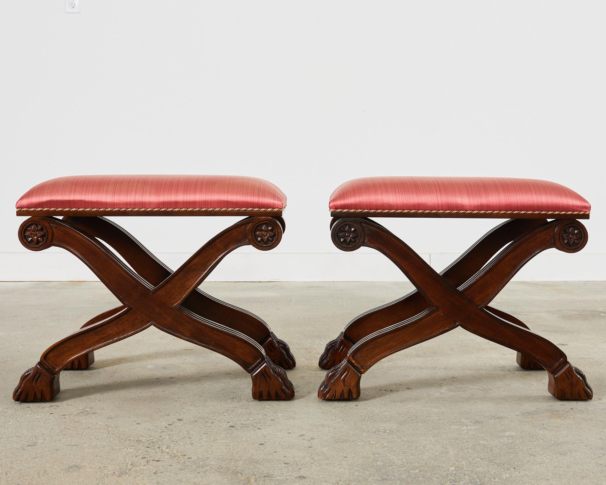 Dramatic pair of x-form curule benches or stools made in the neoclassical style by Century Furniture. The stools are crafted from a rich, walnut frame with reeded legs having carved rosettes on the tops and ending with lions paw feet. The seats are