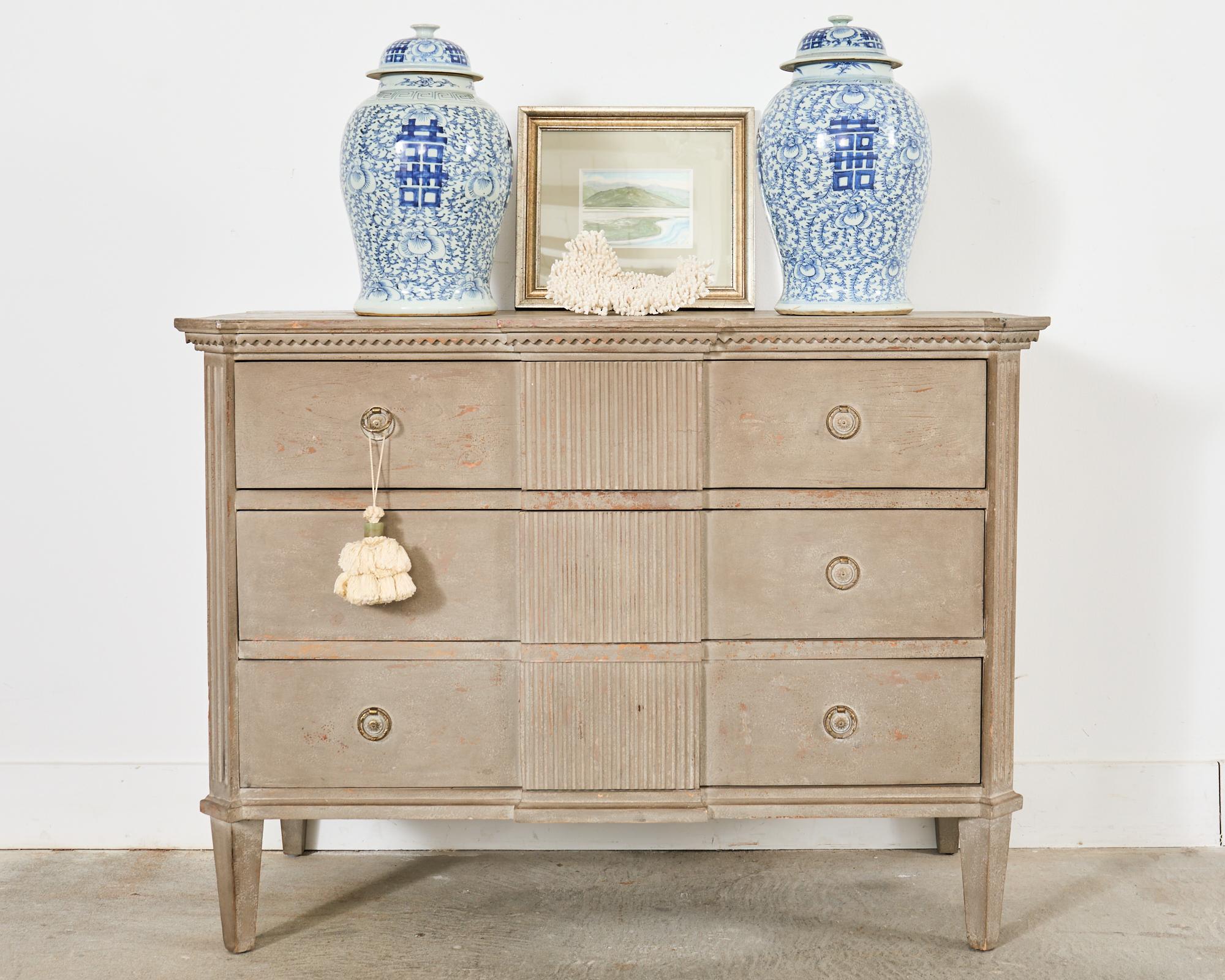 Divine pair of cerused commodes or chests of drawers made in the Swedish Gustavian taste. The large chests feature pilaster column reeded corners. The three drawer cases are centered by a large reeded column motif with a conforming top in the