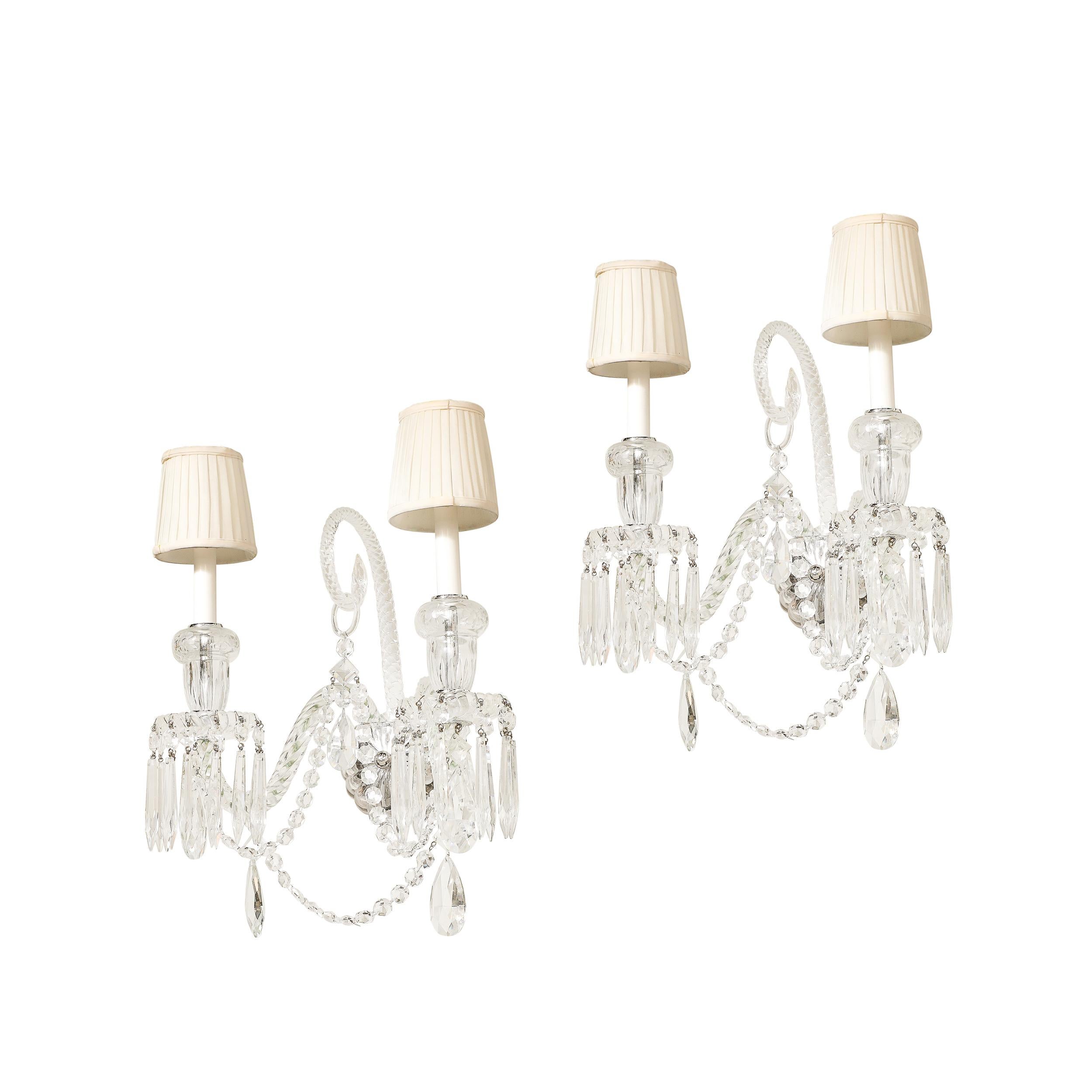 Cette élégante paire d'appliques néoclassiques à deux bras en cristal exsude une sophistication intemporelle, fabriquée à la manière de l'emblématique maison française Baccarat. Ces étonnants luminaires muraux du XXe siècle sont dotés de bras et de