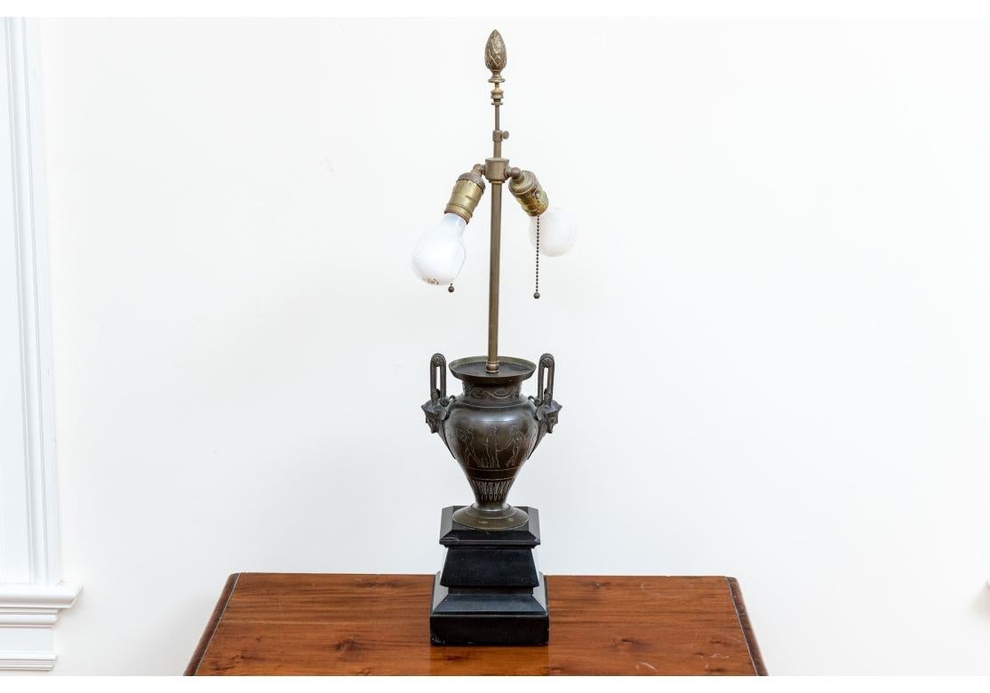 Belles urnes effilées de style néoclassique avec de hautes poignées arquées ornées de rosettes, de masques barbus de style grec et d'attaches en forme de palmettes. Le col est orné de vignes incisées, le corps de figures comprenant des guerriers