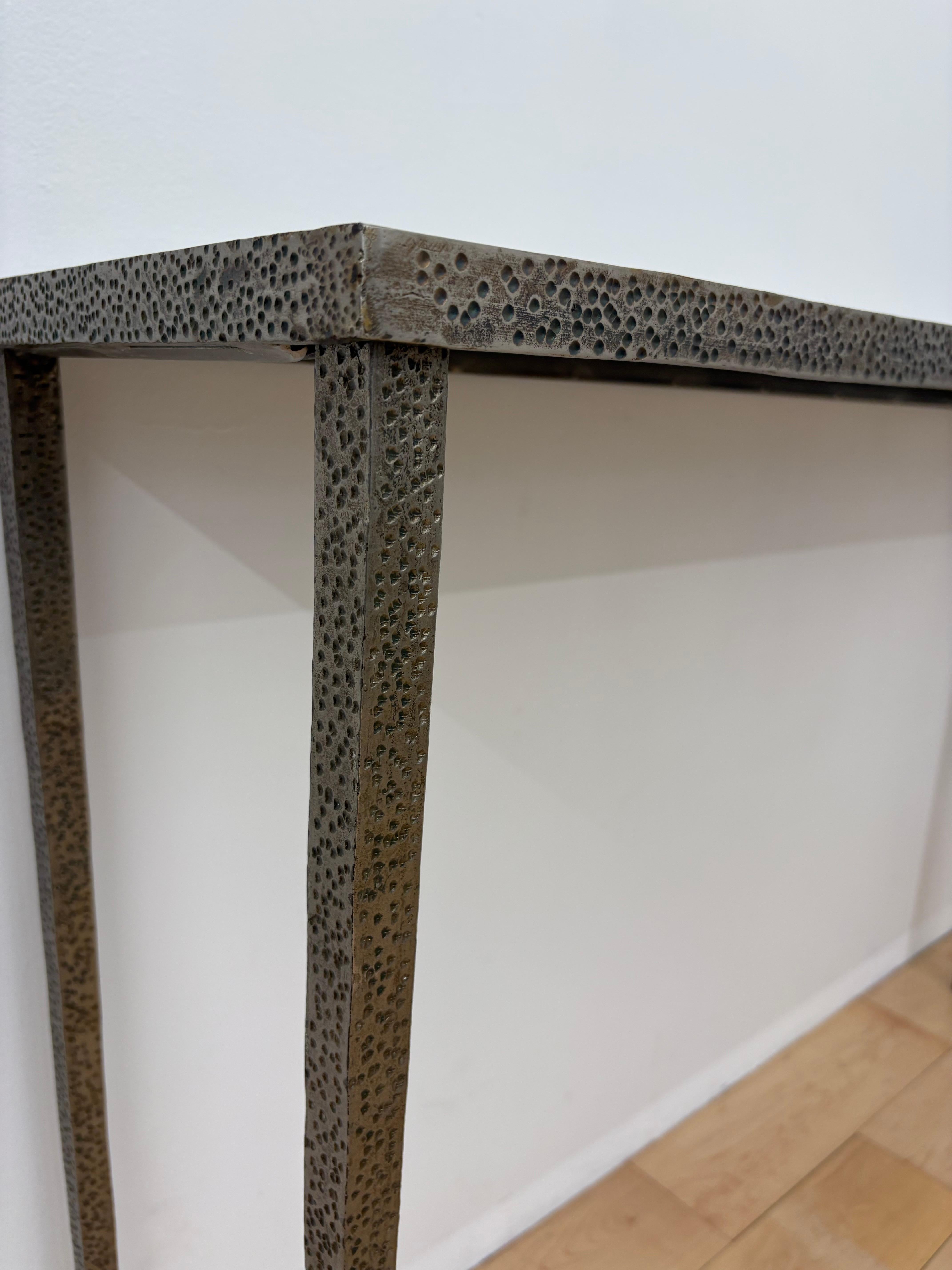 Pair of brushed stainless steel console tables designed in the manner of Jean-Michel Frank, created for the interior designer Meridith Baer. These minimalist forms embrace a distinctly brutalist silhouette, softened by elegantly tapered legs and a