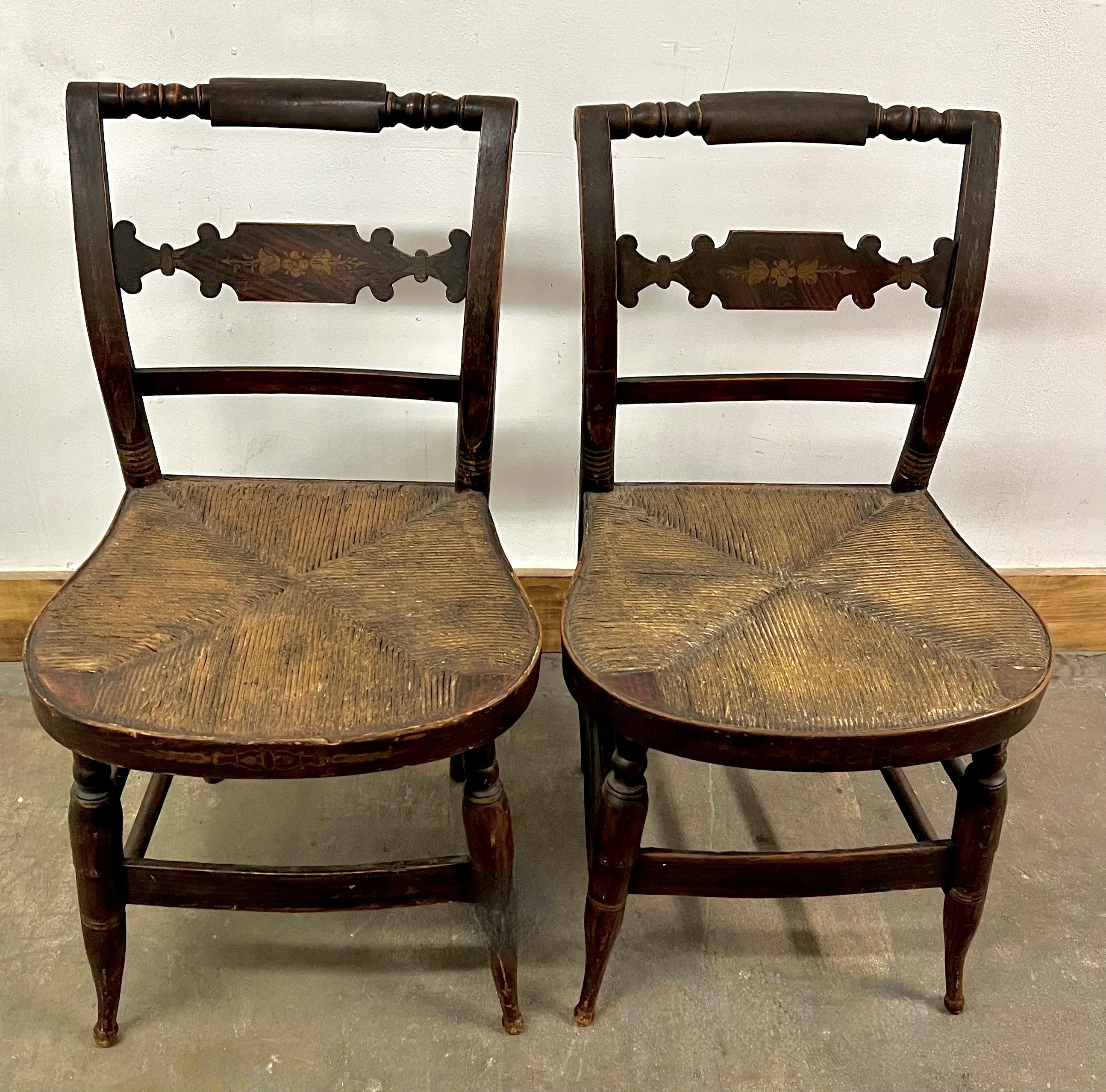 Pair of New England Hitchcock Style or Fancy chairs. Hand painted / stenciled with a deep and rich patination from years of good wear. The seats are woven rush seats and are in very good condition. 

A compliment to many spaces, around a table or