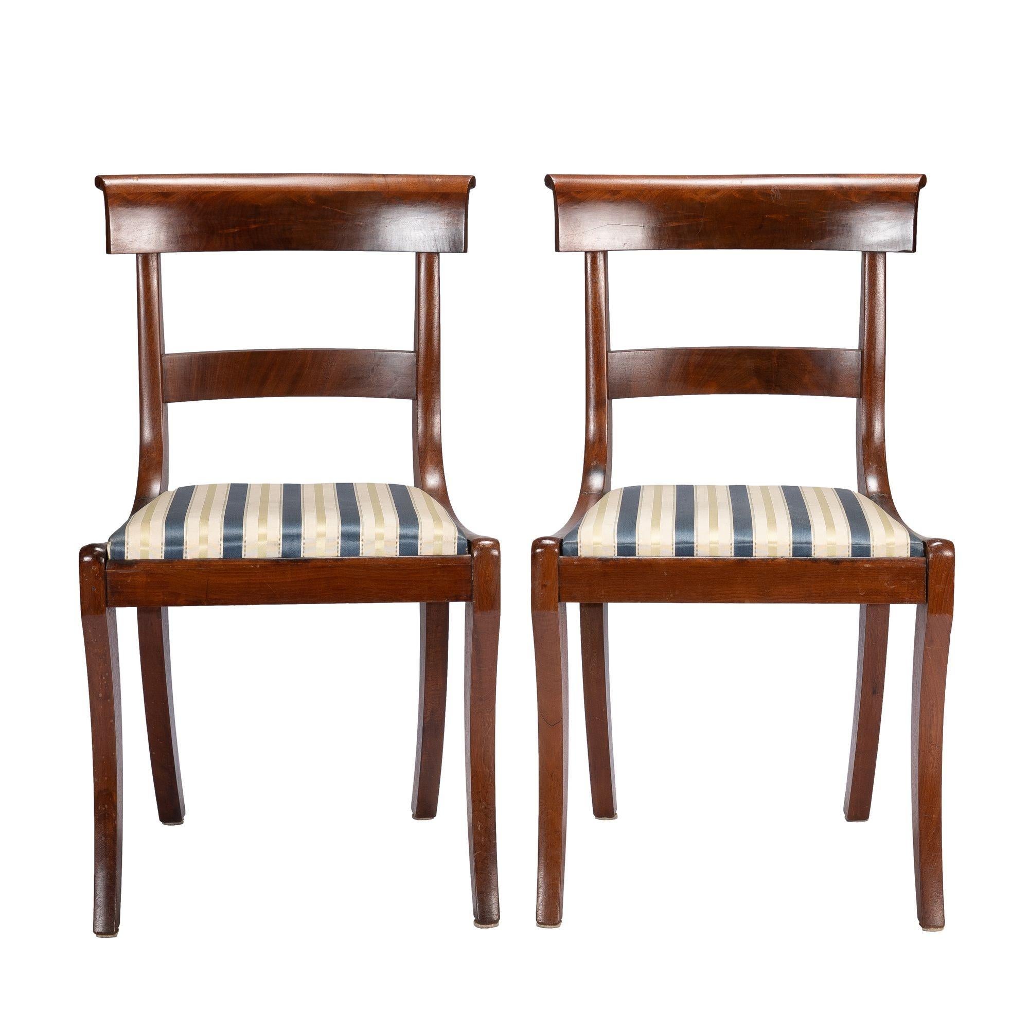 Pair of New York Klismos slip seat side chairs in mahogany and figured mahogany veneers. The chairs have a curved and figured veneer applied crest rail with scrolled edge over a curved and figured veneered horizontal back rail morticed between the