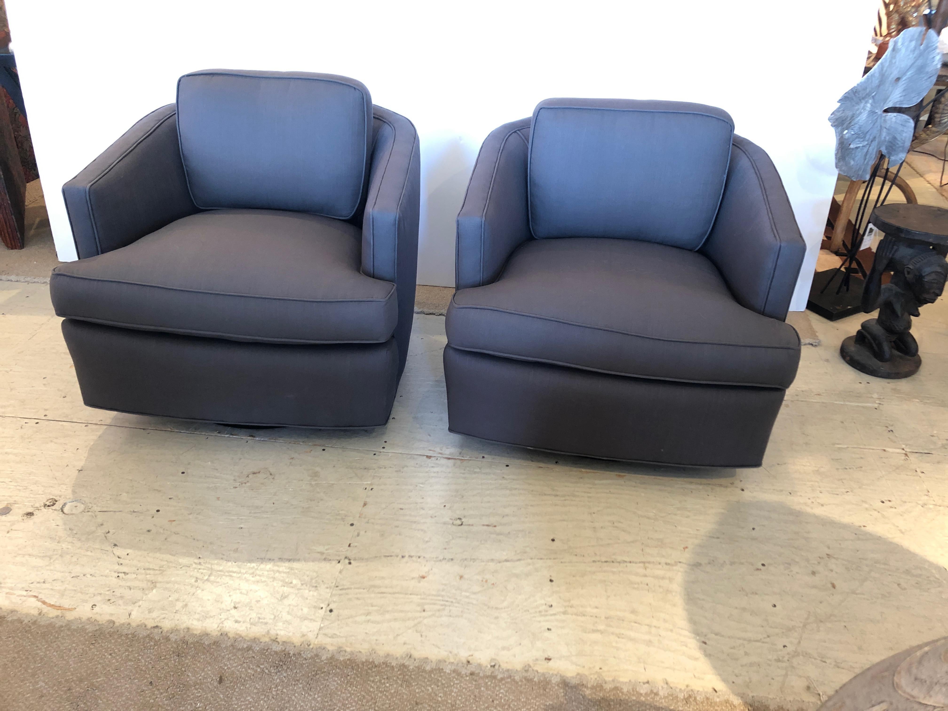 A stunning pair of compact beautifully constructed solid swivel club chairs in the style of Milo Baughman having ebonized round wooden bases and new elegant dark grey linen upholstery.