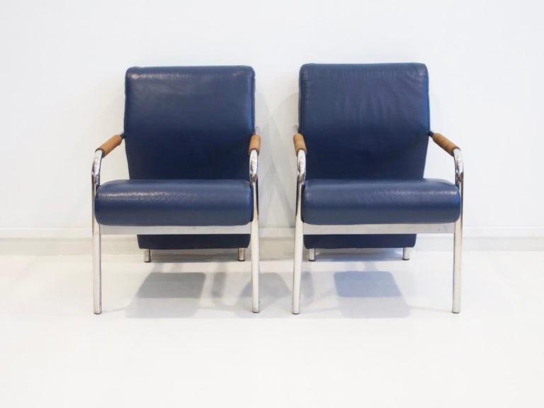 Pair of armchairs, model Niccola, designed in 1993 by Andrea Branzi for Zanotta. Construction on a four-legged tubular steel frame, upholstered and covered in dark blue leather, armrests with brown leather braiding. Manufacturer's name under the