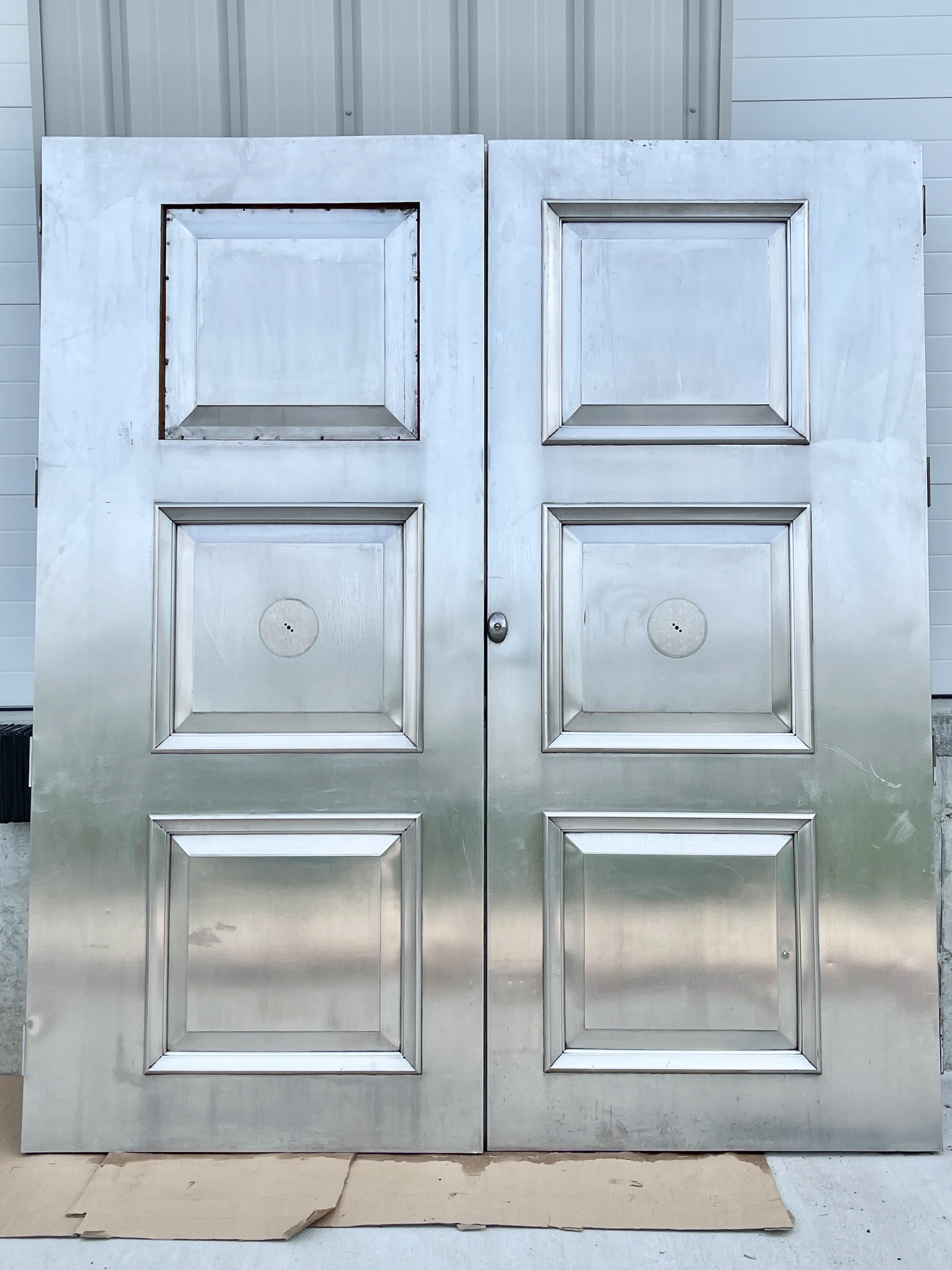 Pair of nickel-silver double entrance doors with three raised square panels, hinges and lock. 
Similar to main entrance doors of Tiffany & Co. but origins unknown.
Sheet metal is very heavy gauge. Inner core appears to be hardwood.
Bring them back