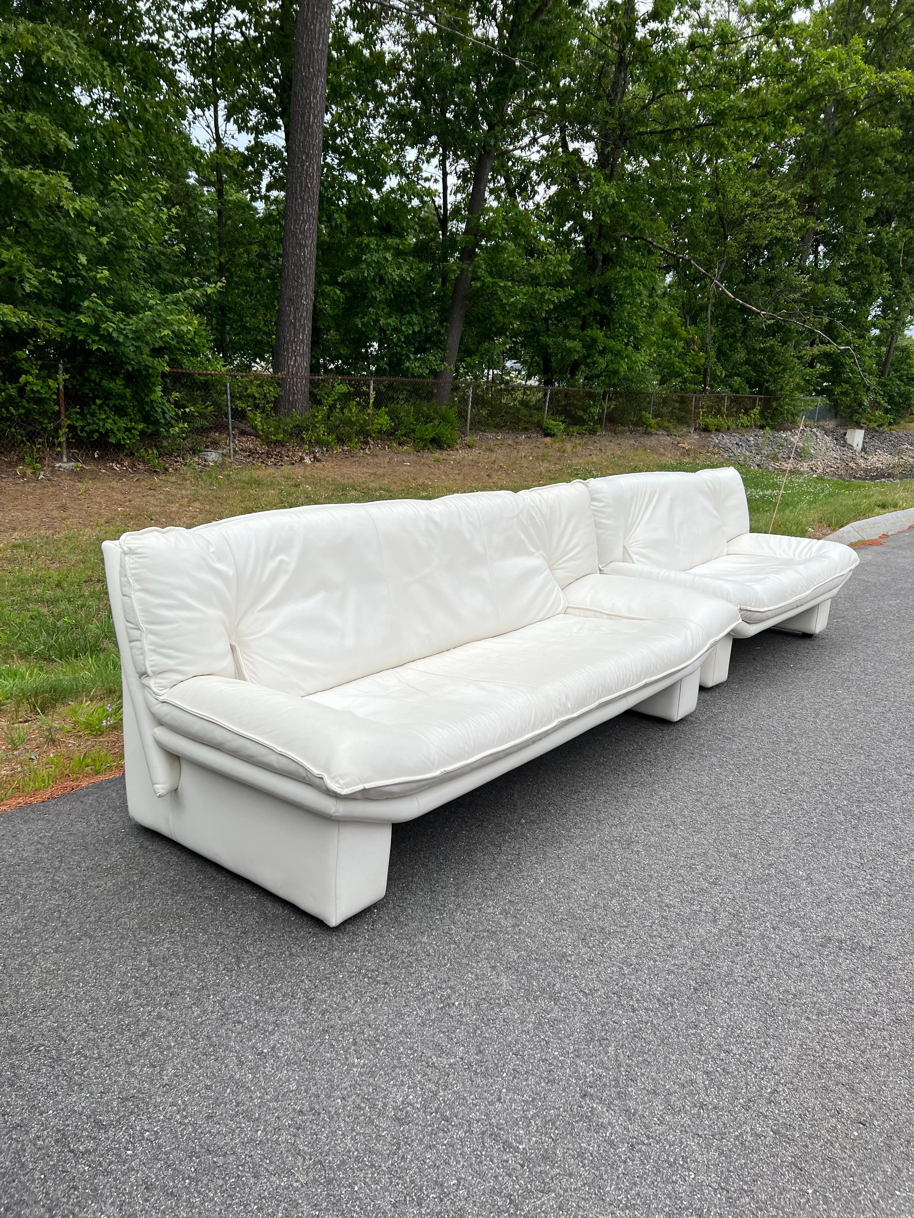 Set of 2 post-modern Italian white leather sofas designed by Nicoletti Salotti. The soft white leather is in good condition overall - some even scuffing/scratching throughout. Some areas are a little more worn/darkened from age and use (see up close