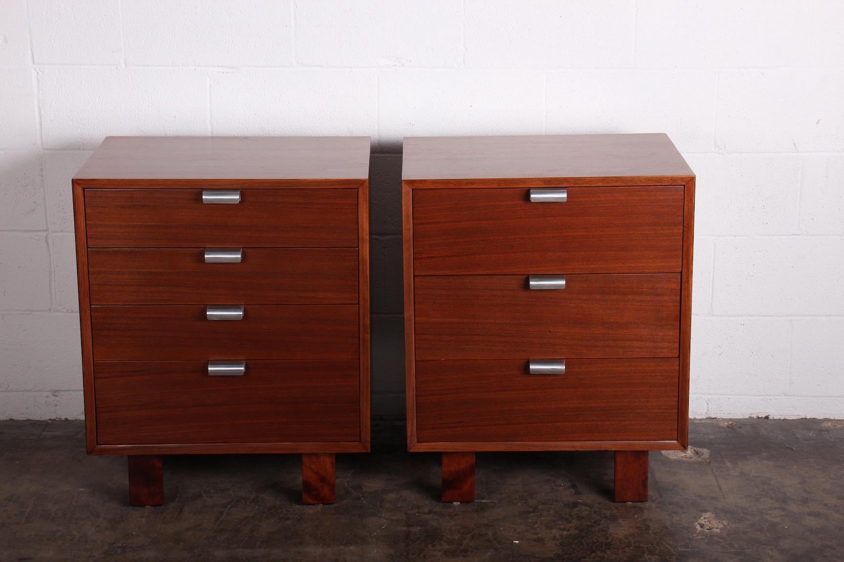 A pair of walnut nightstands with aluminum handles. Designed by George Nelson for Herman Miller.