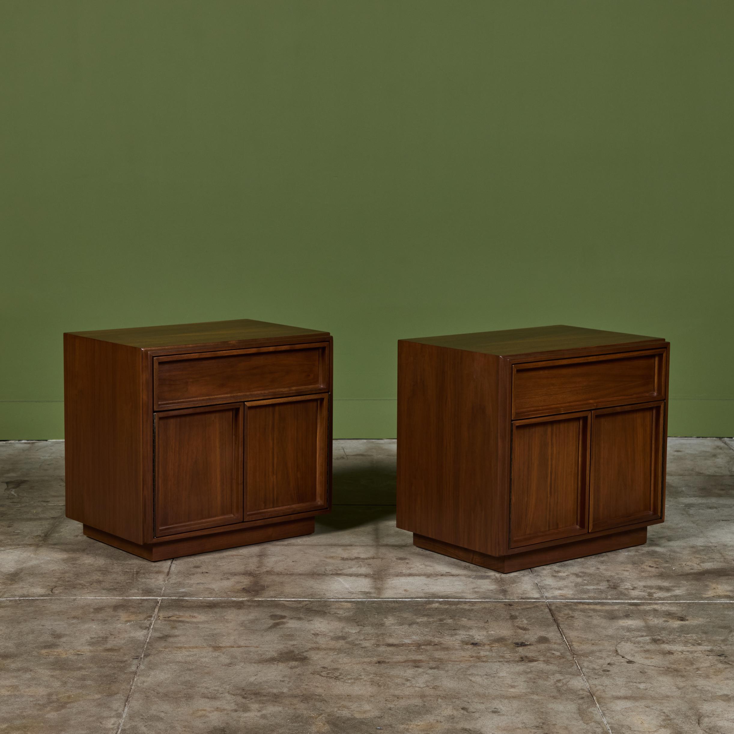 Pair of walnut nightstands by John Keal for Brown Saltman, c.1960s, USA. This minimal design features an upper drawer with two hinged cabinet doors below for additional bedside storage. The nightstands rest on a plinth base. Drawer is marked - Brown