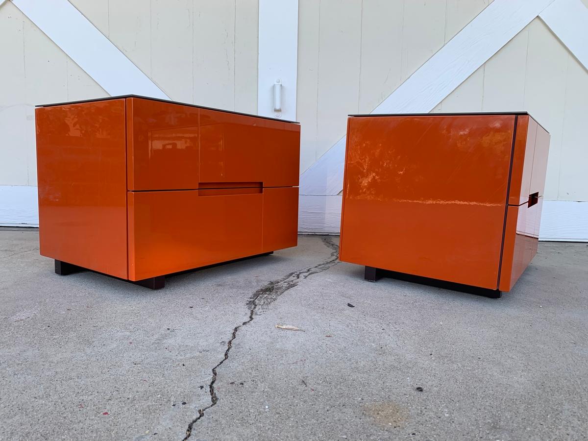 Beautiful pair of nightstands in orange lacqered finish, never used however one of them has some scratches on the side from when they were moved, they may be able to polish out.

The piece have glass tops and are really