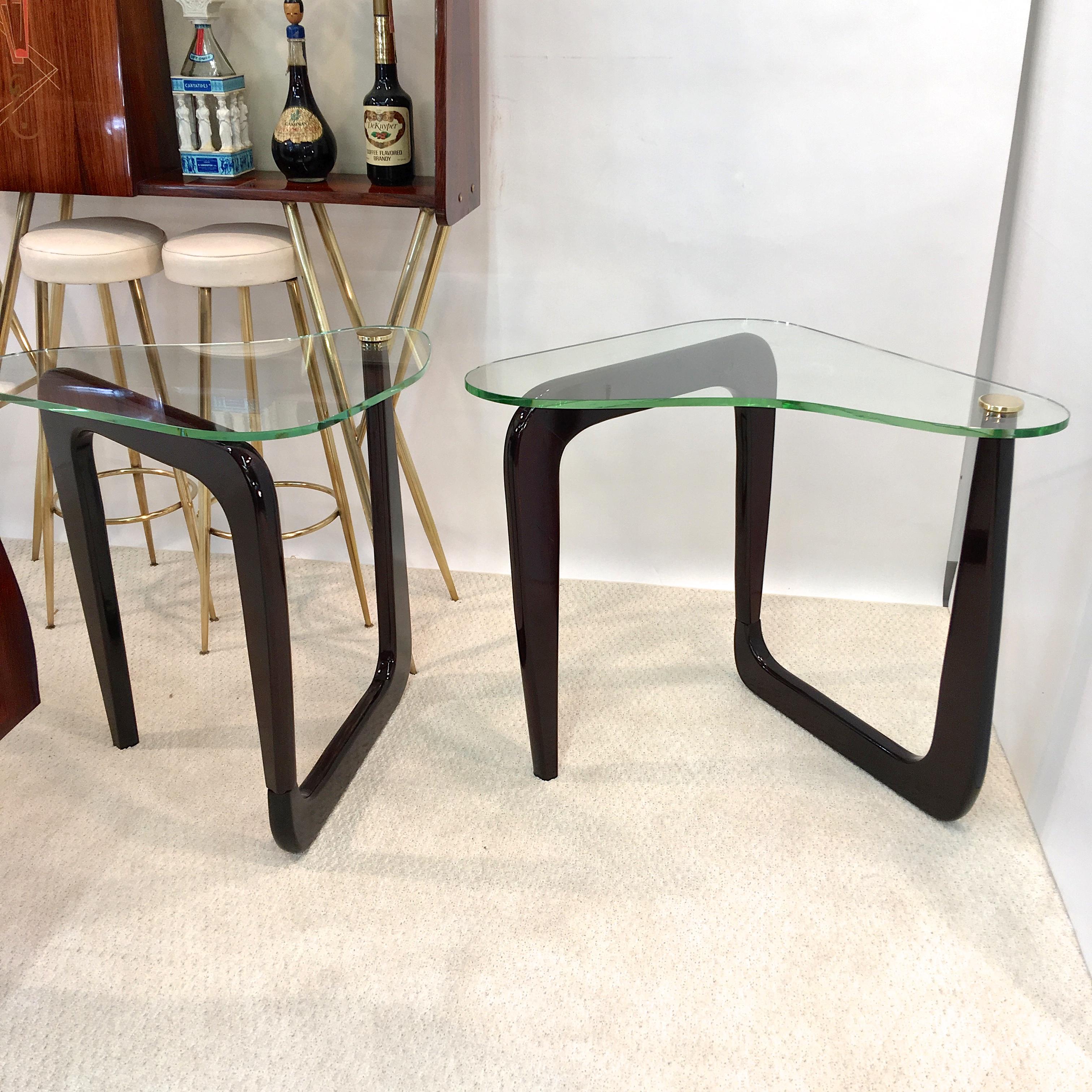 Pair of vintage 1960s sculptural and adjustable serpentine side or end tables, quite tall at 27 inches high, in ebonized oak topped with biomorphic shaped 3/8 inch thick glass top which is secured by a polished solid brass screw disk. The bases