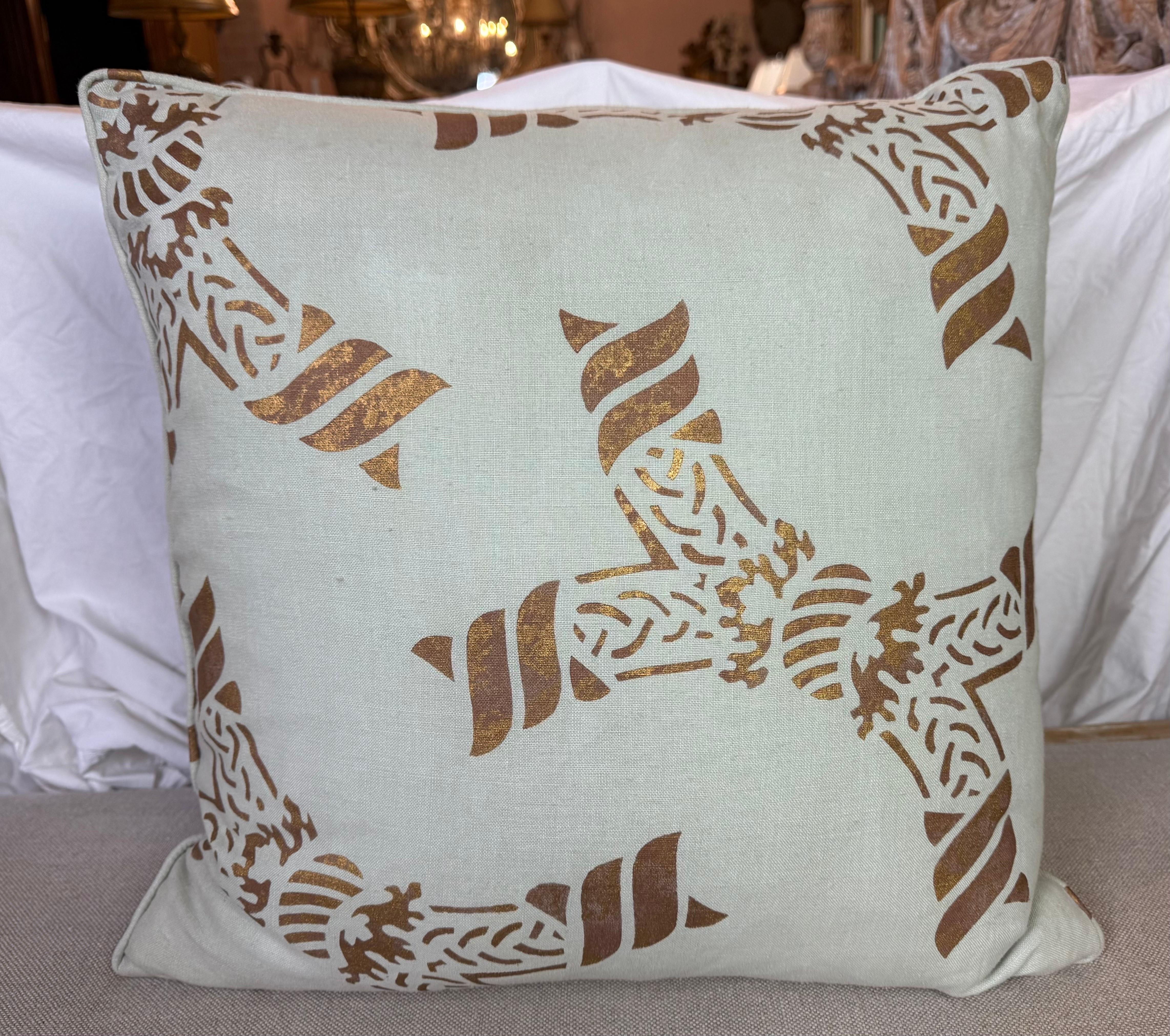 Questi cuscini sono realizzati in lino Nomi, decorato a mano, con un disegno intricato e simmetrico nei toni del blu e del marrone dorato. La parte anteriore presenta un motivo audace che ricorda i motivi tradizionali o antichi, aggiungendo un tocco