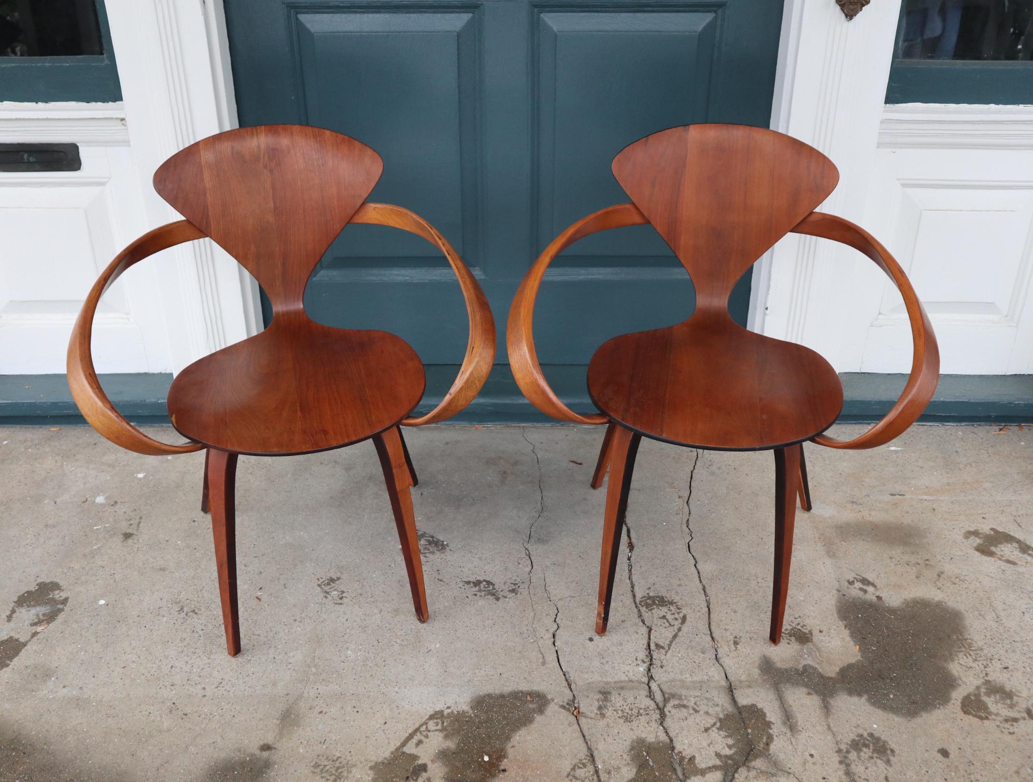 Gorgeous pair of Pretzel arm chairs designed by Norman Cherner and manufactured by Plycraft. Sculptural best wood arms and walnut seat show lovely color and form. One of the finest American chair designs of the 20th century. No breaks at the right