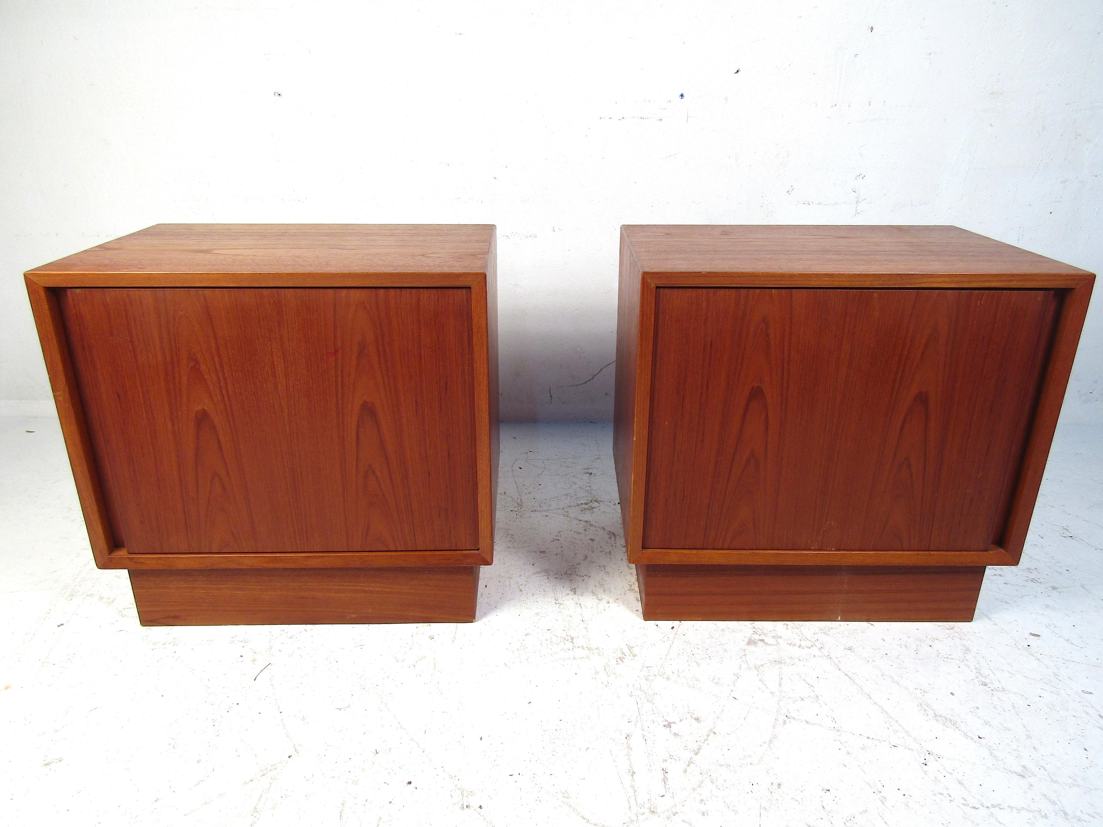 Pareja de mesillas de noche noruegas de teca. De diseño sencillo y elegante, presenta líneas limpias con un armario de apertura frontal en cualquiera de las dos piezas. Ambos soportes tienen un estante interior con una base 