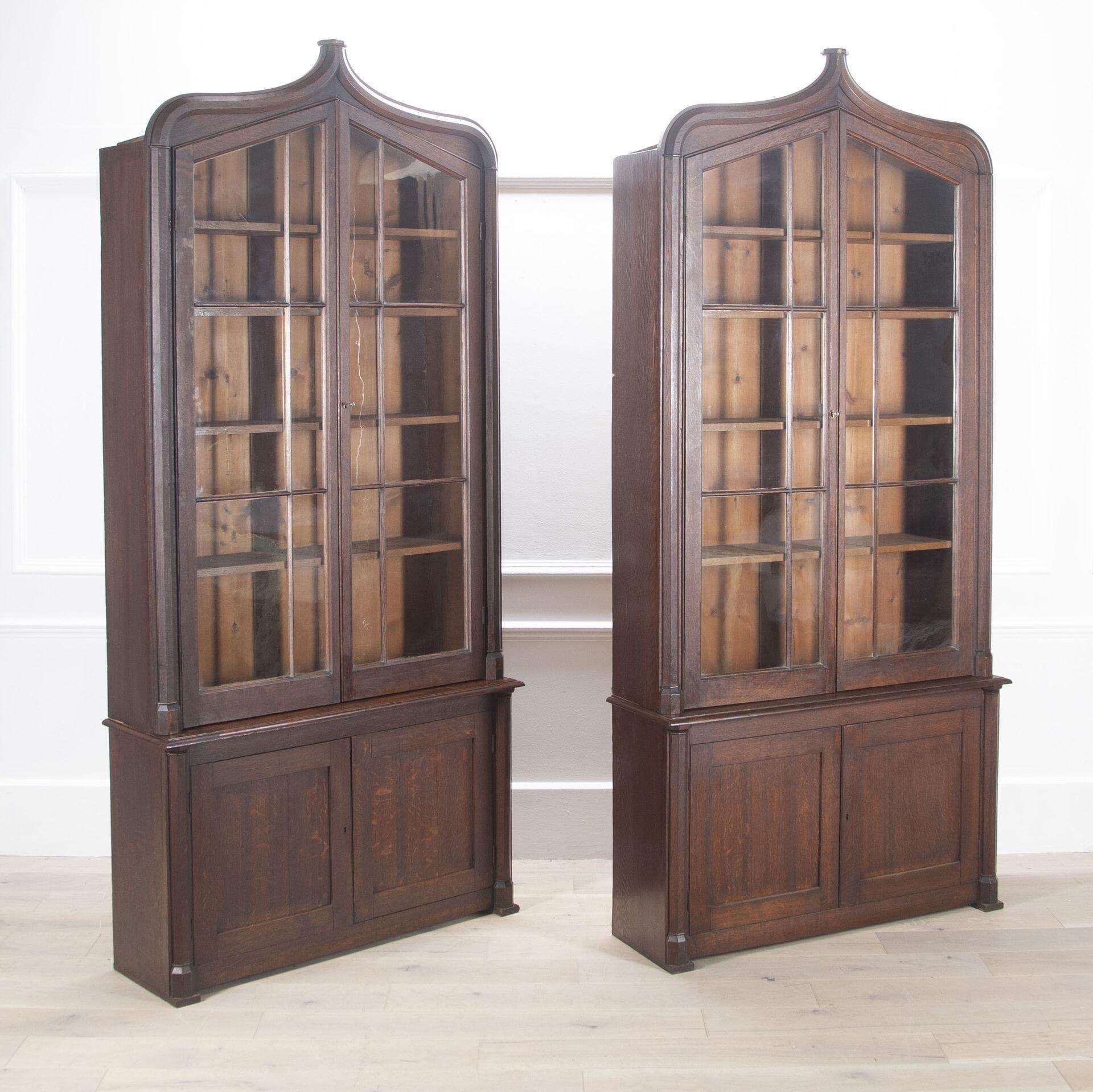 Fine and impressive pair of 19th Century oak bookcases in the gothic manner.

The upper sections with glazed doors enclosing an arrangement of shelves, the bases having twin doors to each enclosing a cupboard, the whole supported on block feet.

A