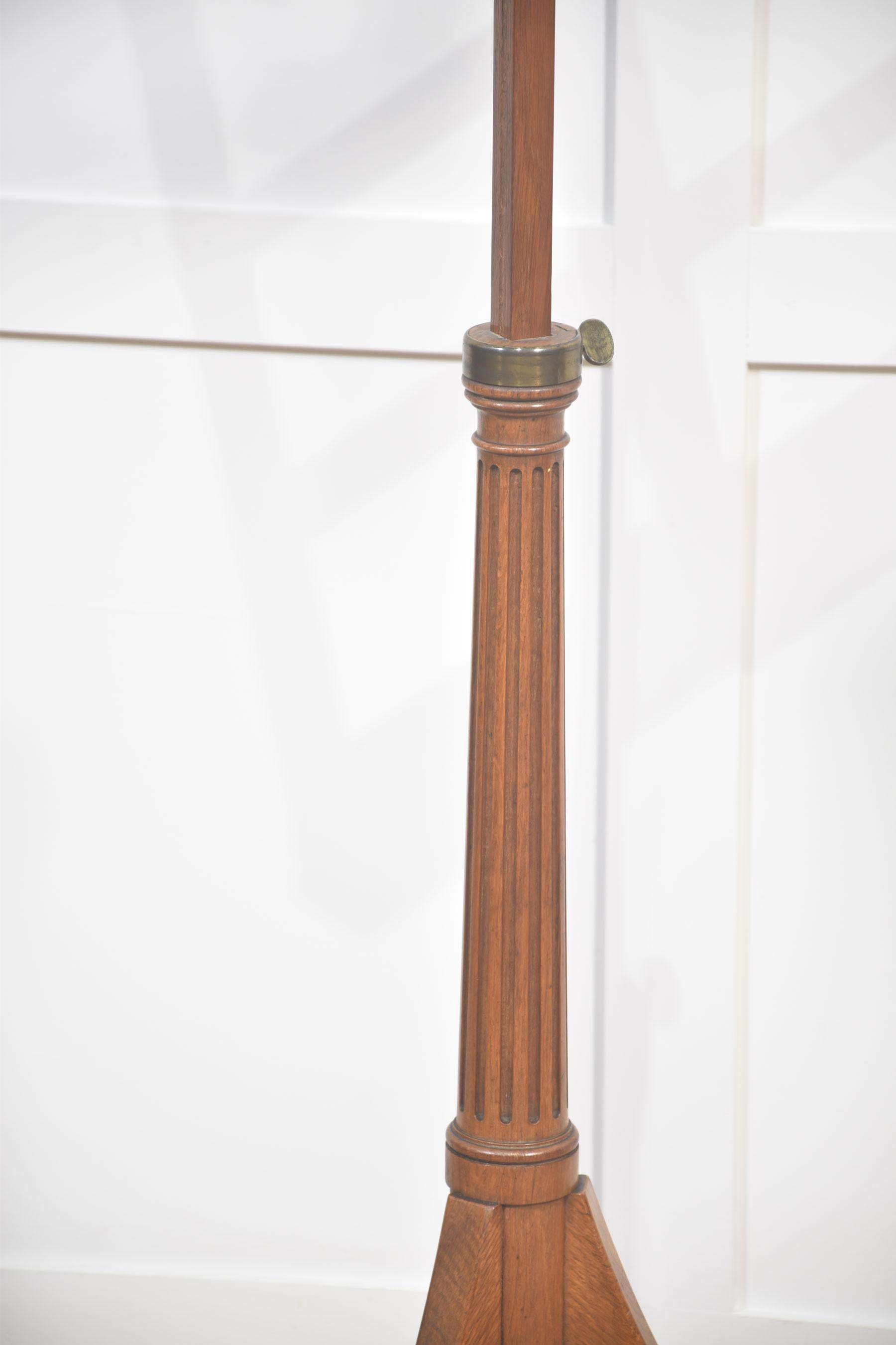 A refined pair of adjustable music stands, beautifully handcrafted from solid oak with a rich, mellow patina that highlights the natural grain of the wood. Each stand features a fluted central column and a tripod base with brass castors, combining