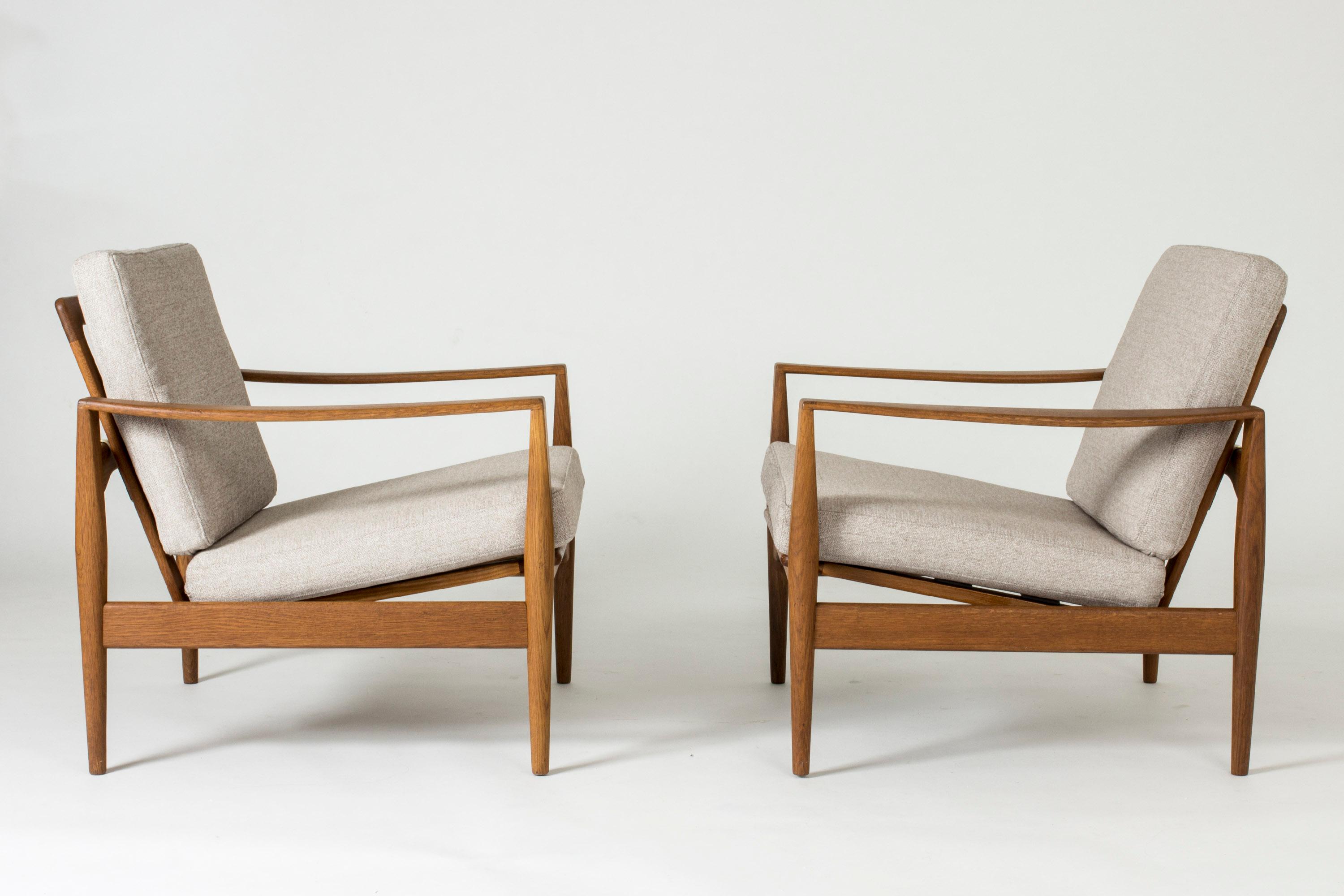 Pair of oak lounge chairs by Illum Wikkelsø in a casually elegant design. Cool open silhouettes with distinct lines, decorative joinery on the armrests.
  