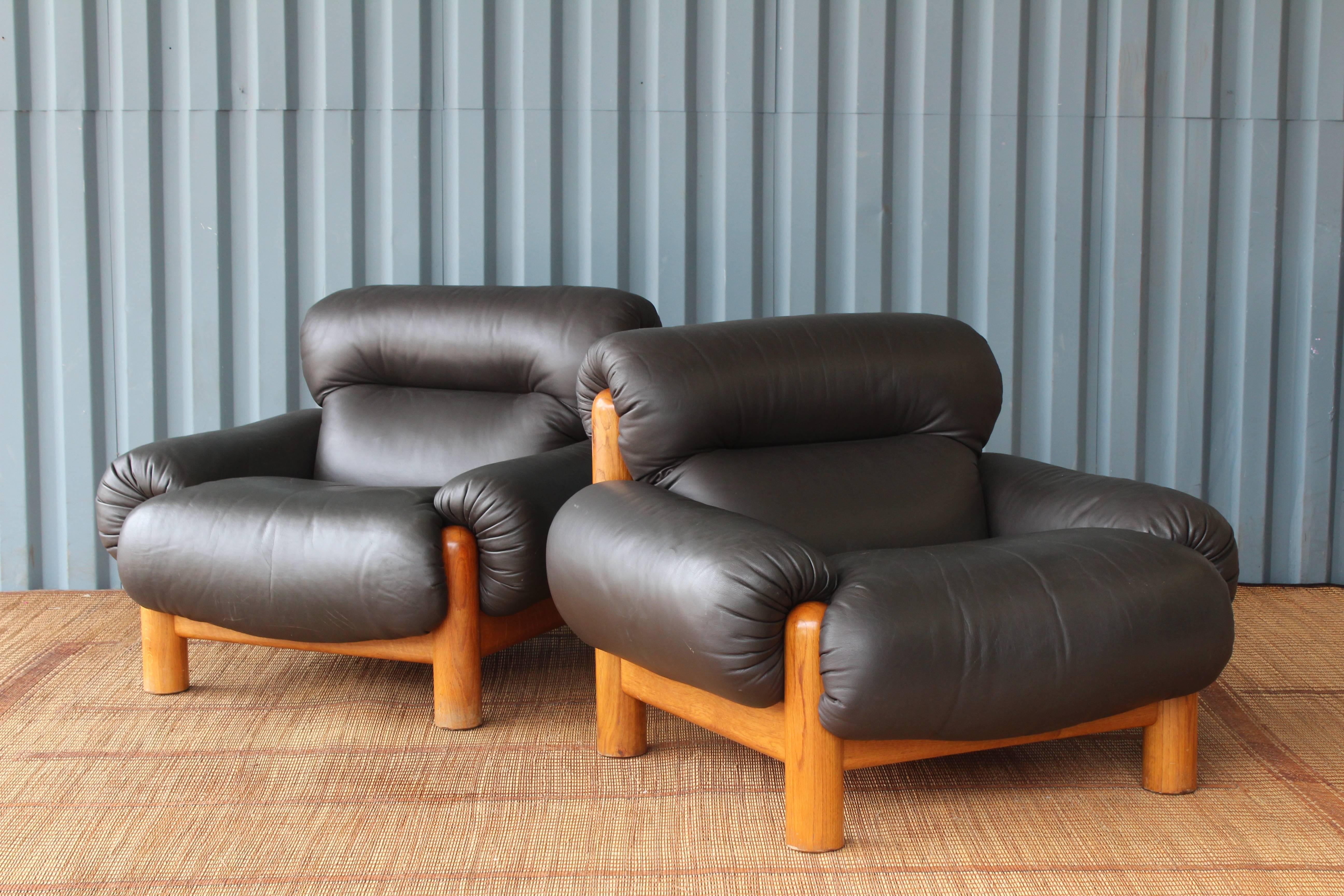 Pair of large and overstuffed lounge chairs with oak frames and leather upholstery. The pair are in fantastic condition.