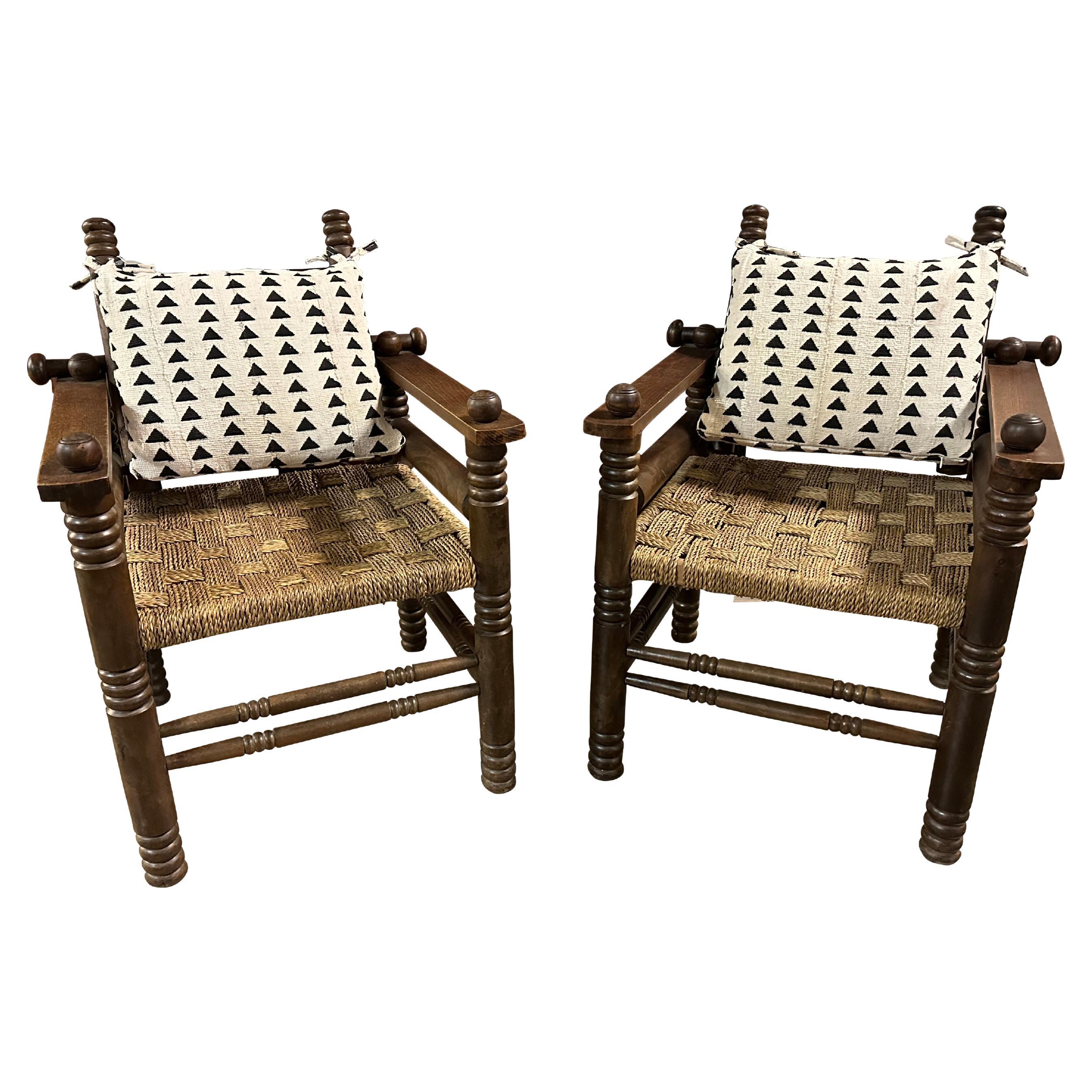 Pair of armchairs in stained oak and rush by collectible art deco designer, Charles Dudouyt.  Well-crafted hardwood frames with stylized lathe turned details support a woven rush seat on an articulating back rest.  Newly made back cushions in black