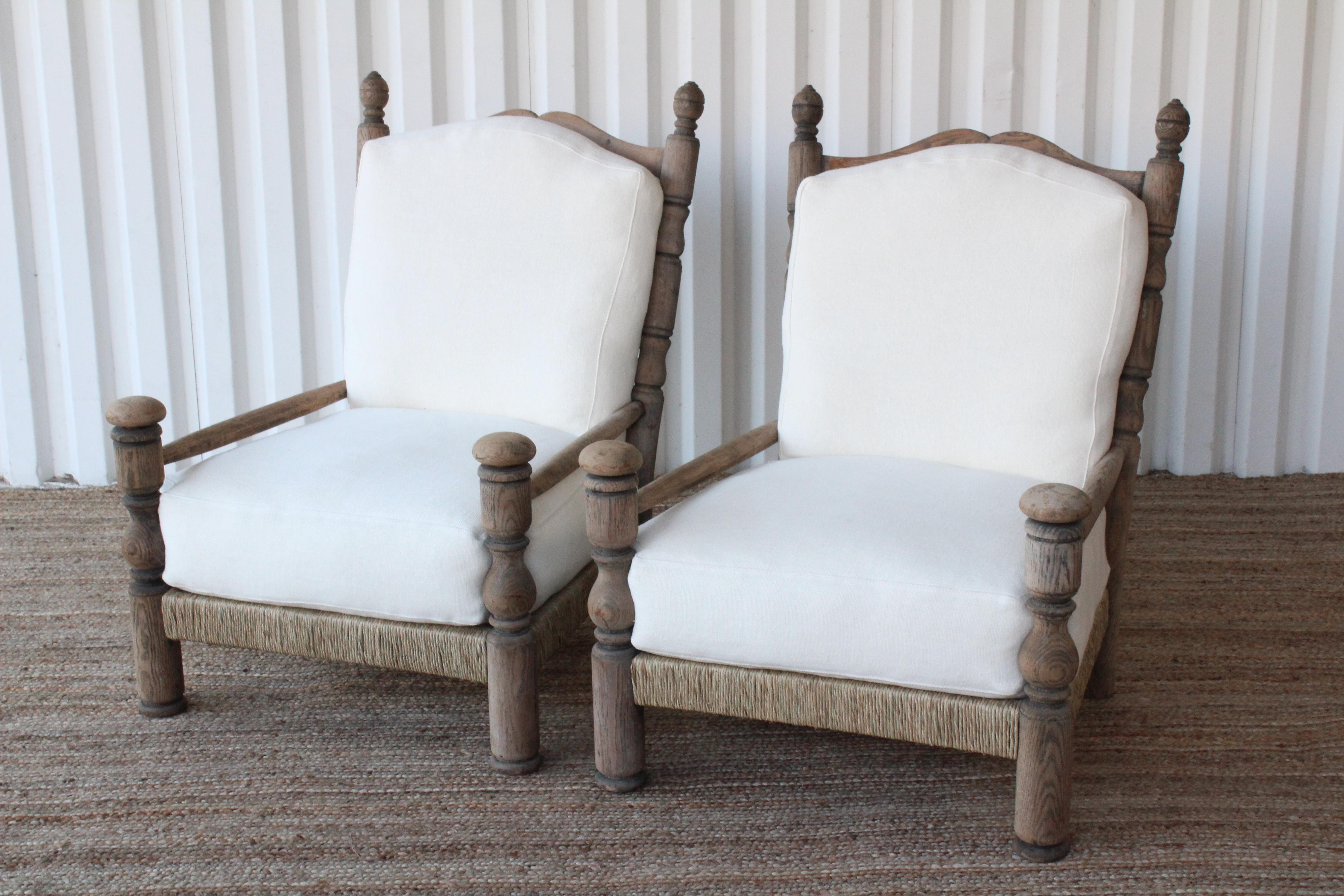 Pair of vintage oak and rush lounge chairs, France, 1950s. Made of solid oak with newly woven rush seats. New upholstered cushions in a white Belgian linen fabric. Cushions inserts are foam and down filled. Oak finish shows wear and patina. The