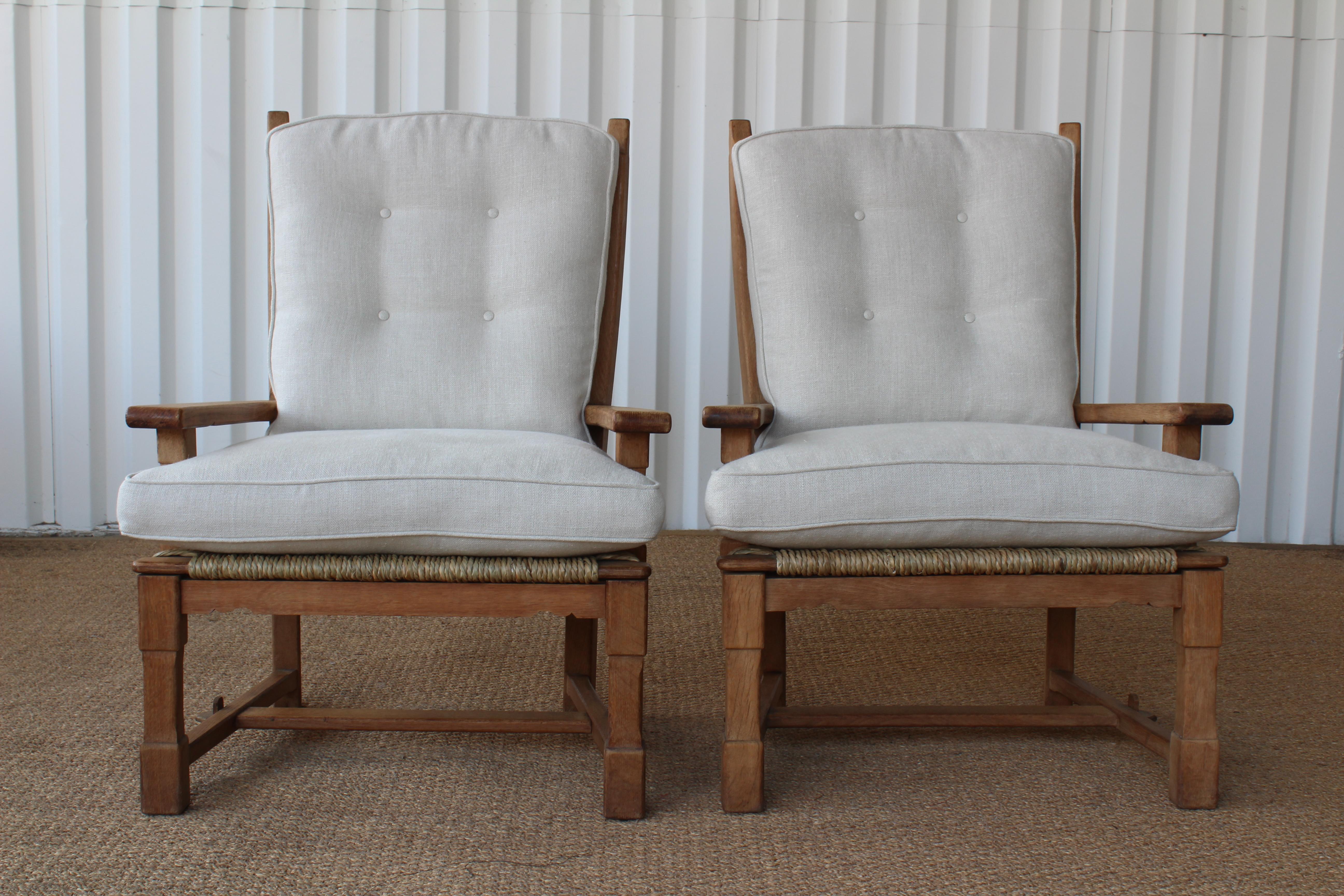 Pair of oak chairs with new seagrass detailing along bottom seat. New straps and new cushions upholstered in an off white Belgian linen. Sold as a pair.