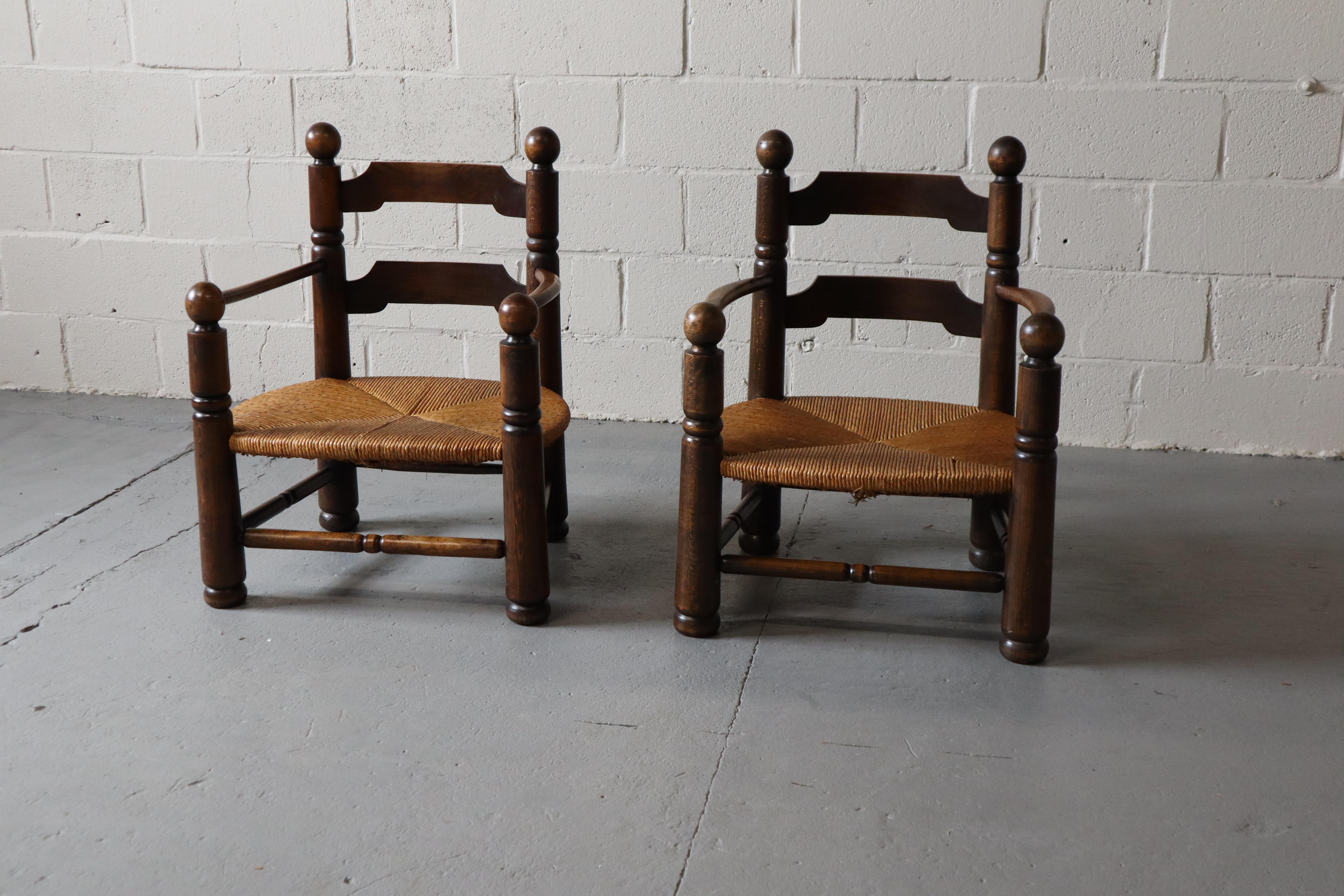 Pair of carved oak armchairs with low rushed seats by French designer Charles Dudouyt, 1940's. He designed these chairs as fireplace chairs.

