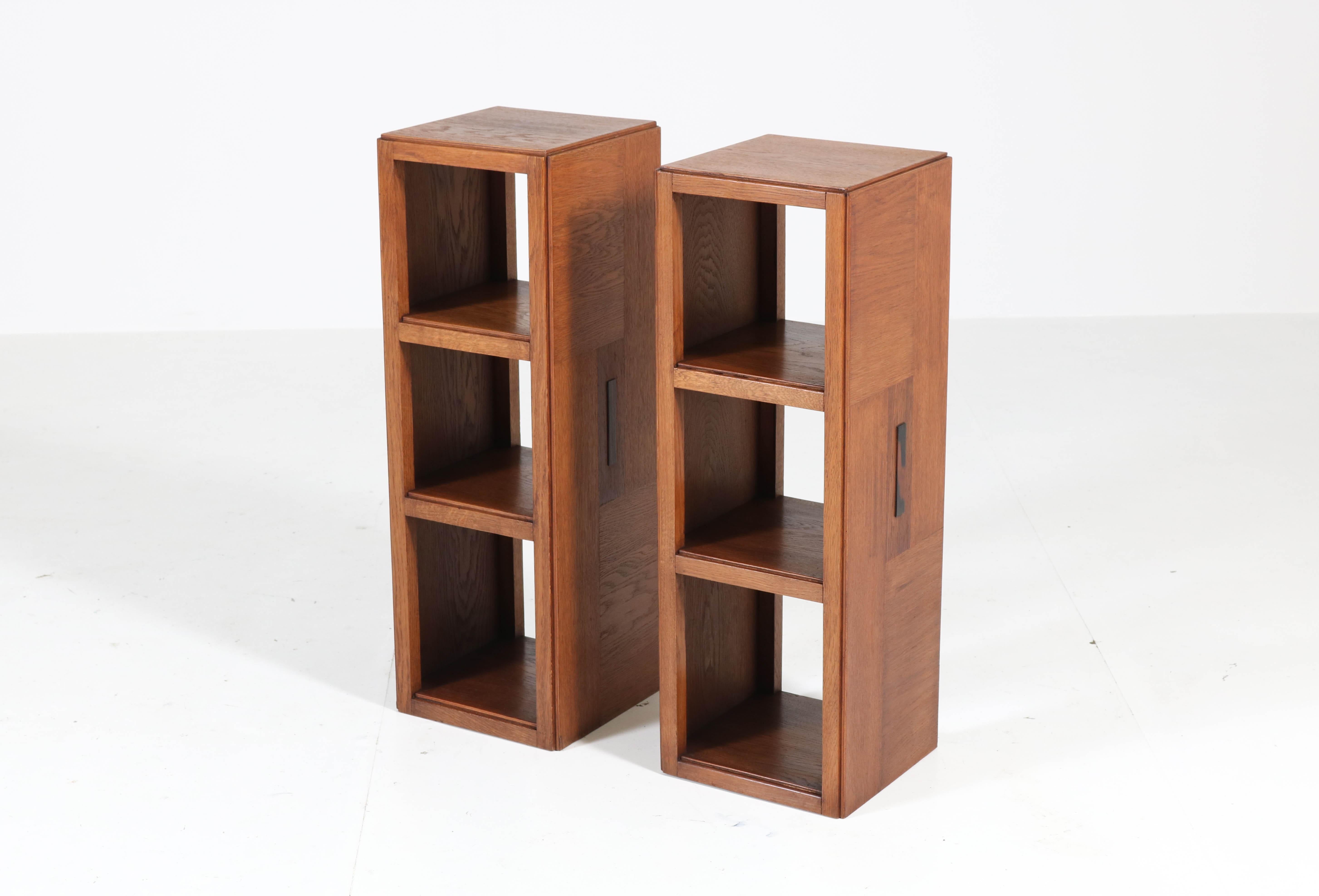 Stunning and rare pair of Art Deco Haagse School pedestal tables or open bookcases.
Design by P.E.L. Izeren for Genneper Molen.
Striking Dutch design from the twenties.
Solid oak and oak veneer with ebony Macassar lining.
In good original