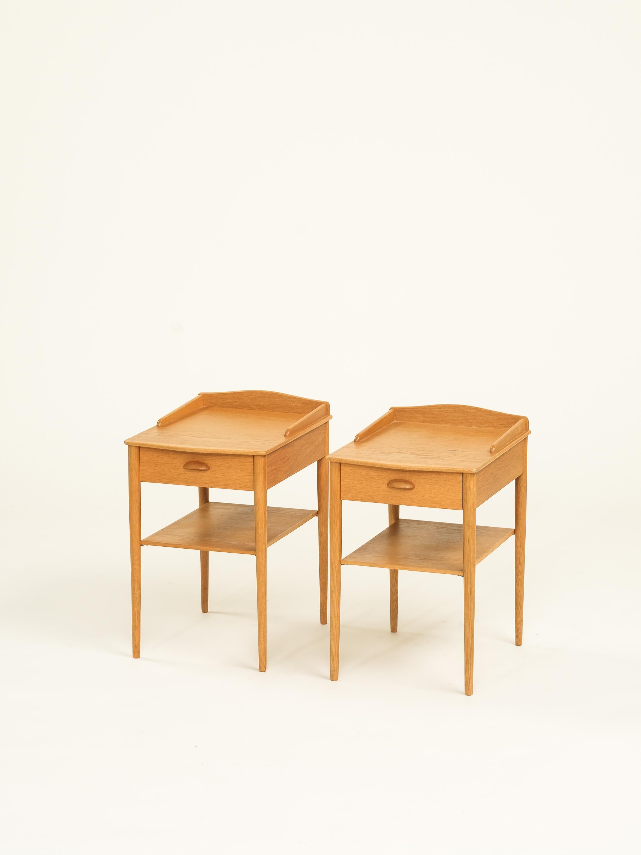 Introducing a stunning pair of Swedish oak bedside tables. Manufactured by Ab Erik Andersson for Rottne, Sweden, 1960s These tables, dating back to the 1960s, are made of oak and showcase a minimalistic design with exquisite attention to