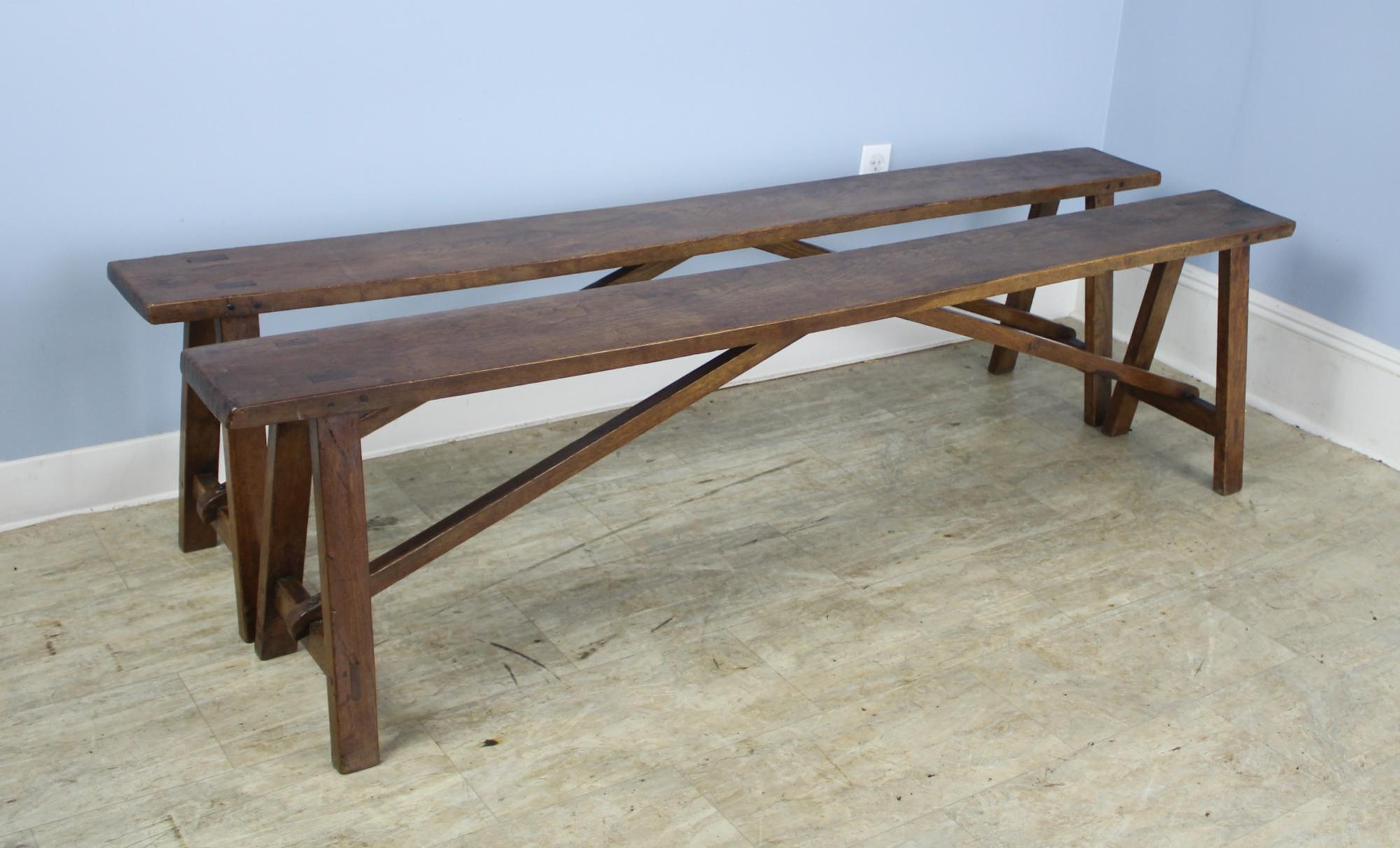 A pair of antique oak benches to put alongside a farm table or provide seating in any room. These two are in very good antique condition with very nice color and patina. Sturdy with good seating height.  These benches have a complementary farm table