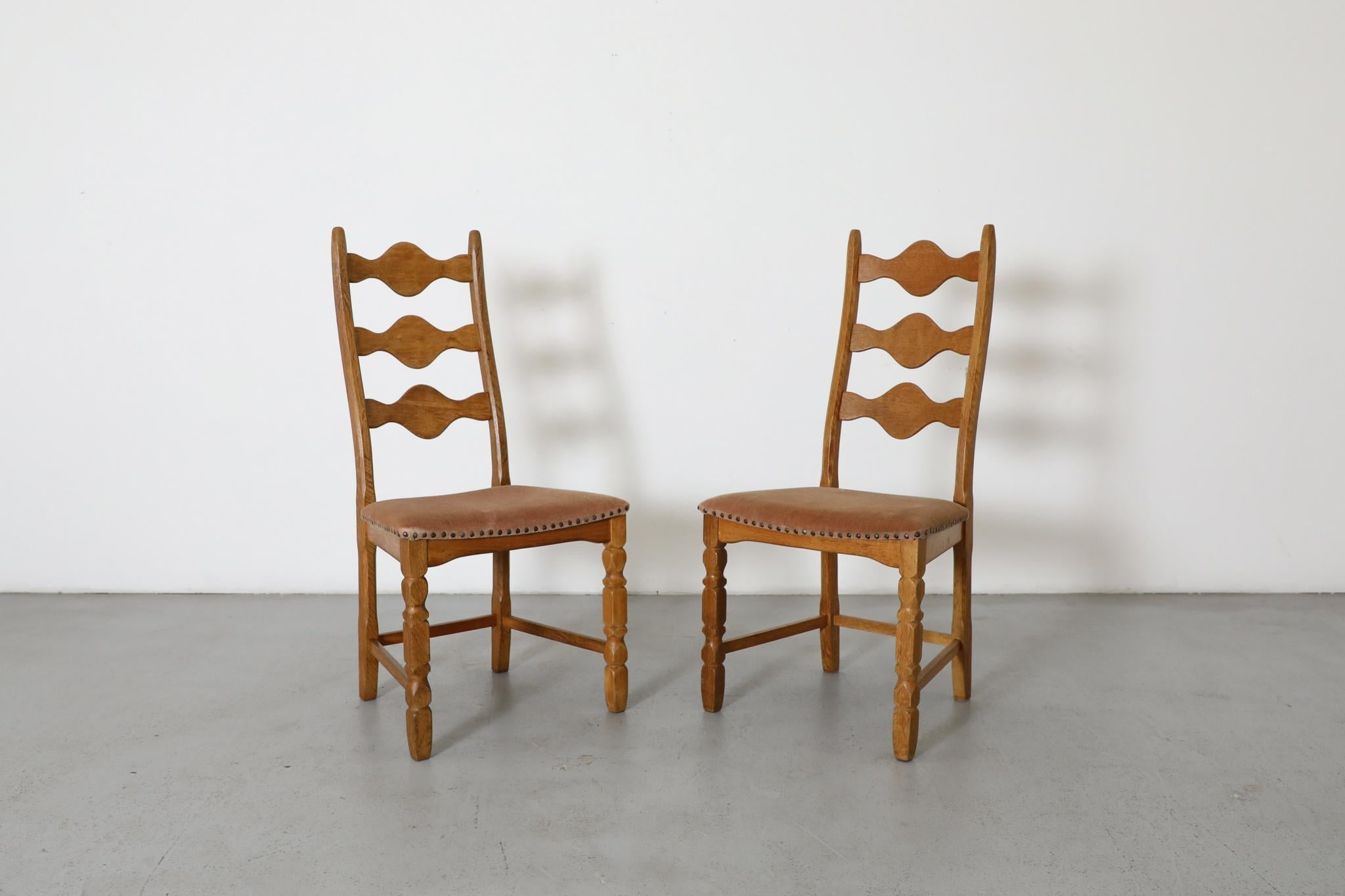 Brutalist decorative back, throne-like oak chairs designed by Henning Kjaernulf. These chairs have  solid oak frames with an undulating decorative design theme and dusty rose velvet upholstered seats with metal studding. In original condition with