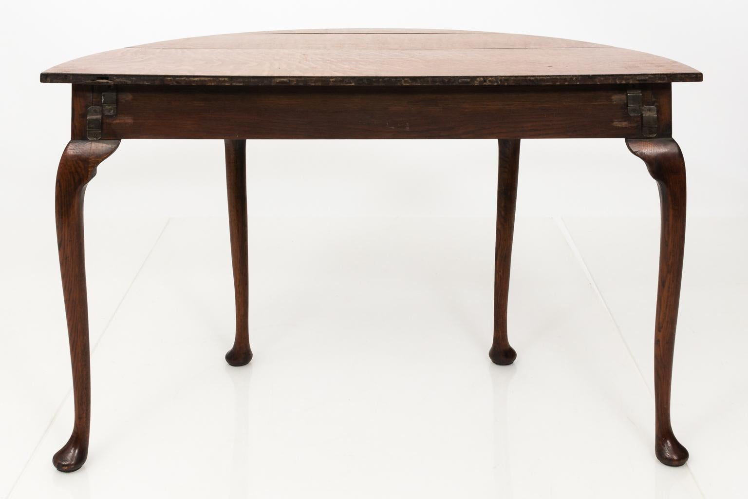 Pair of oak demilune tables with pad feet, circa 1740. The back of each piece features mortise and tenon slots to create a circular center table.