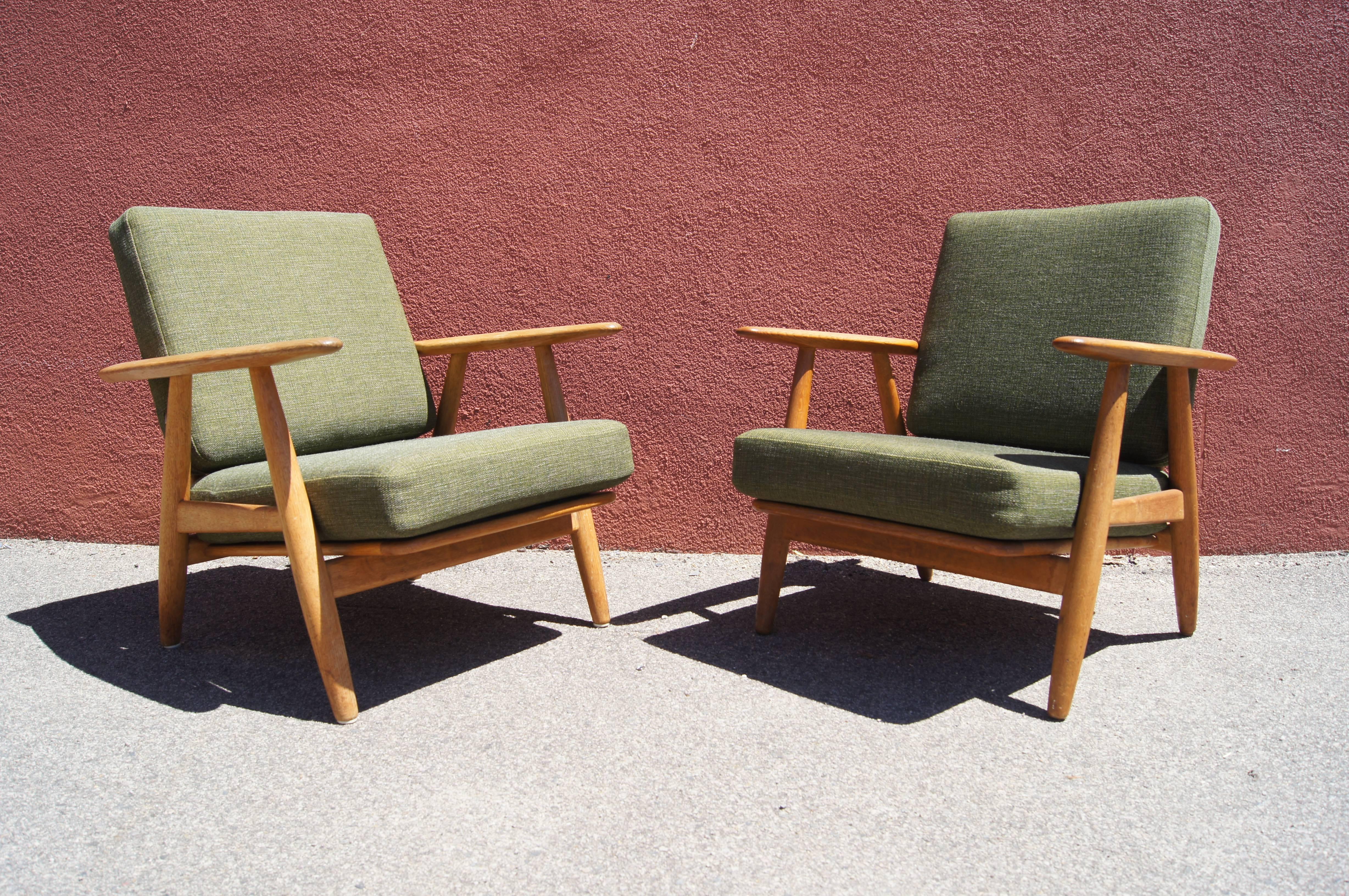 Hans Wegner designed these lounge chairs, model GE240, for GETAMA in 1955. The gently curved armrests of the solid oak frame inspired its popular name: the cigar chair. This pair features new foam cushions upholstered in a restful moss green.