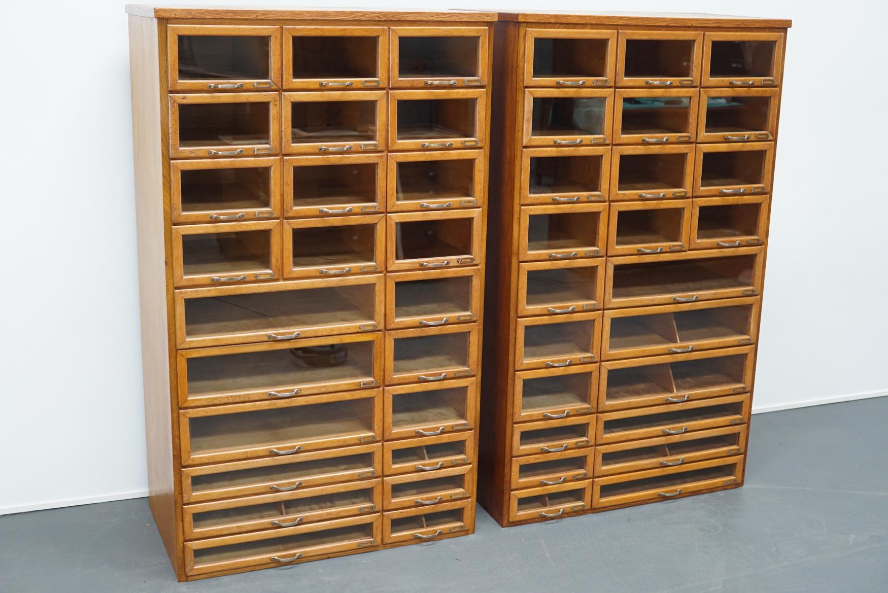 These vintage haberdashery shop cabinets originate from the United Kingdom. The pieces are made from oak and feature 24 drawers each in different sizes. The price listed is for one cabinet and they will be sold separately or together as a pair.