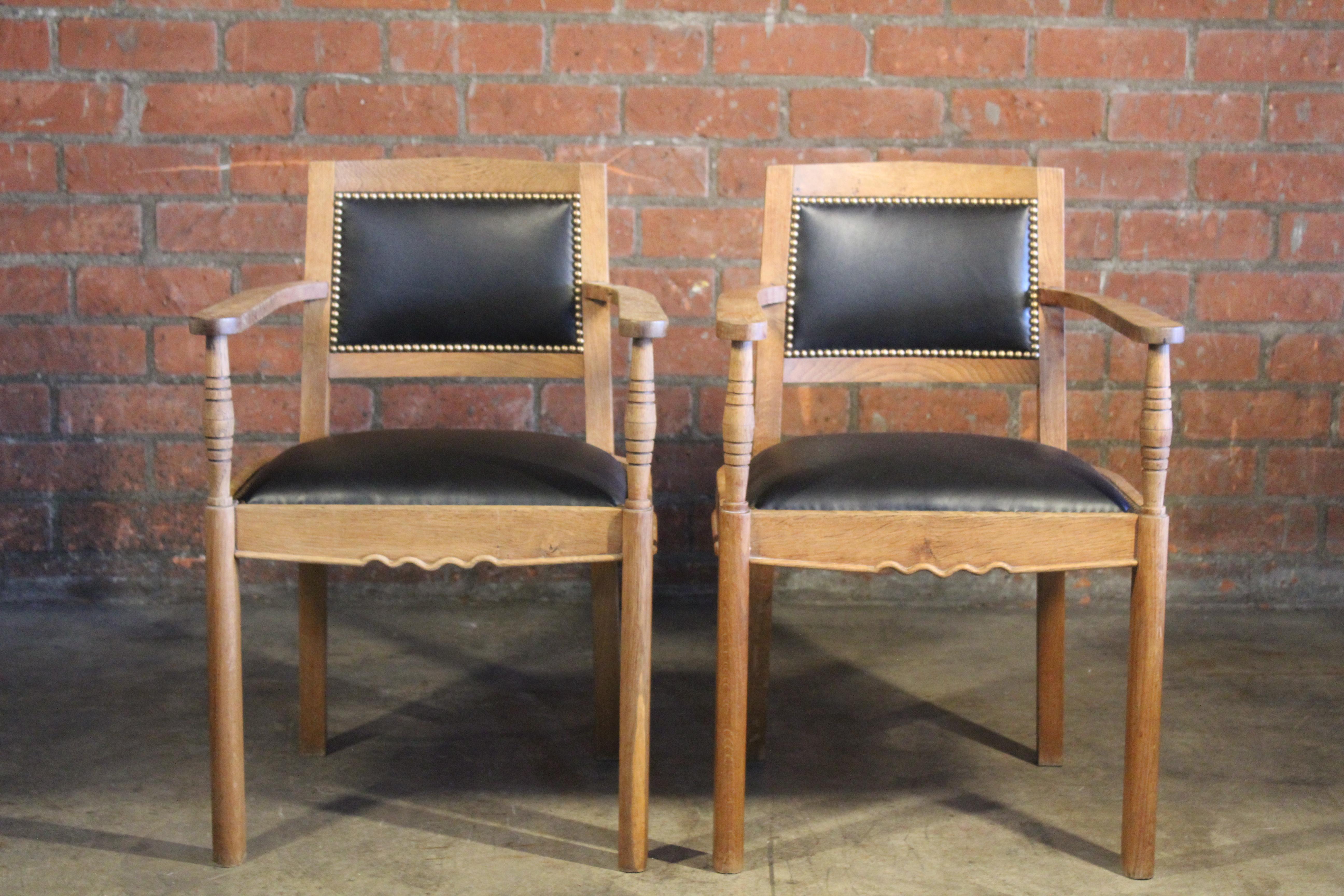 Pair of oak armchairs attributed to Charles Dudoyt. Newly upholstered in black leather with brass nailheads.