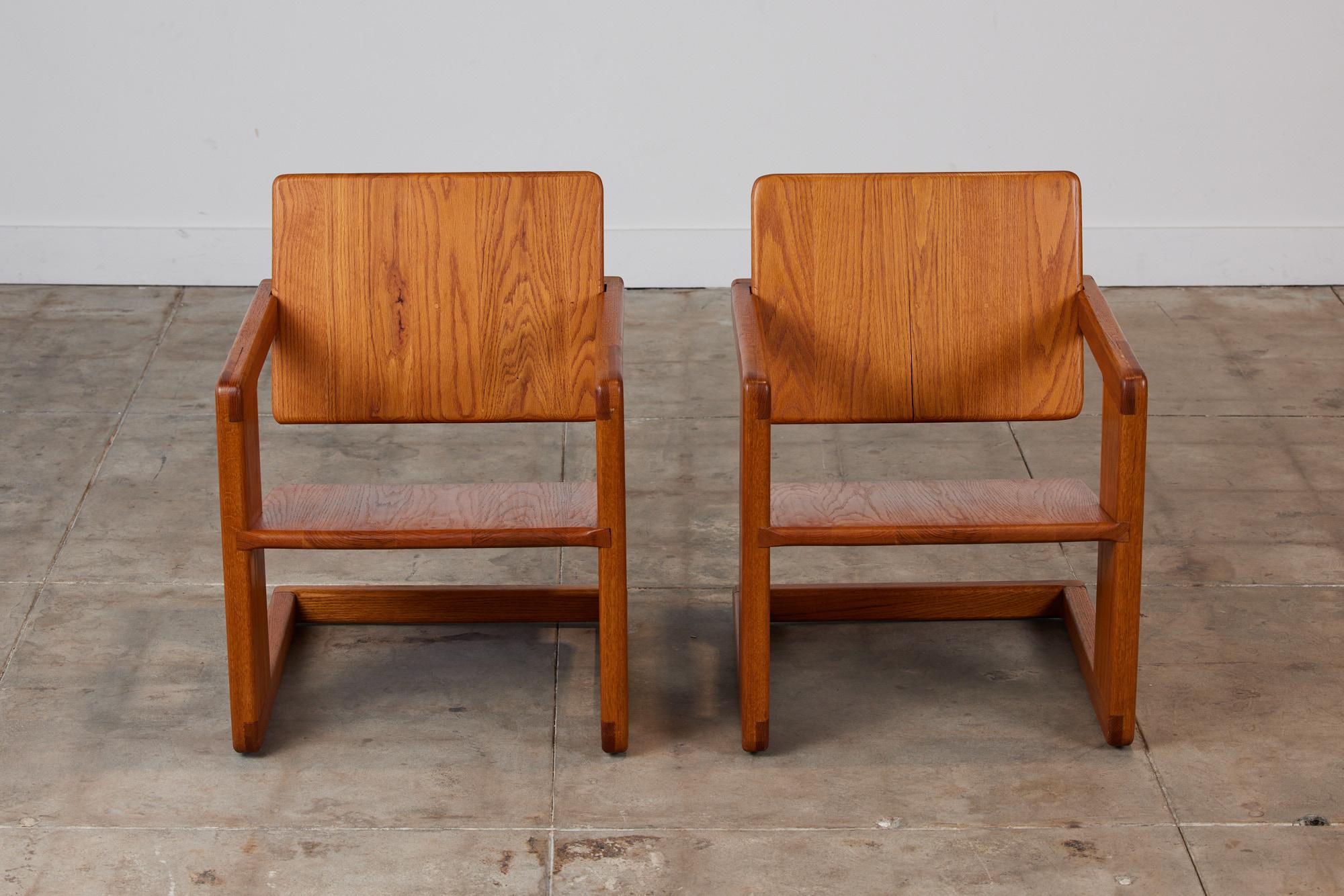 Pair of cantilevered lounge chairs in the style of Lou Hodges. The solid oak frame features cantilevered seats that appear to float inside the frame. Each chair has a pivoting back rest to optimize comfort.

Dimensions: 23.75