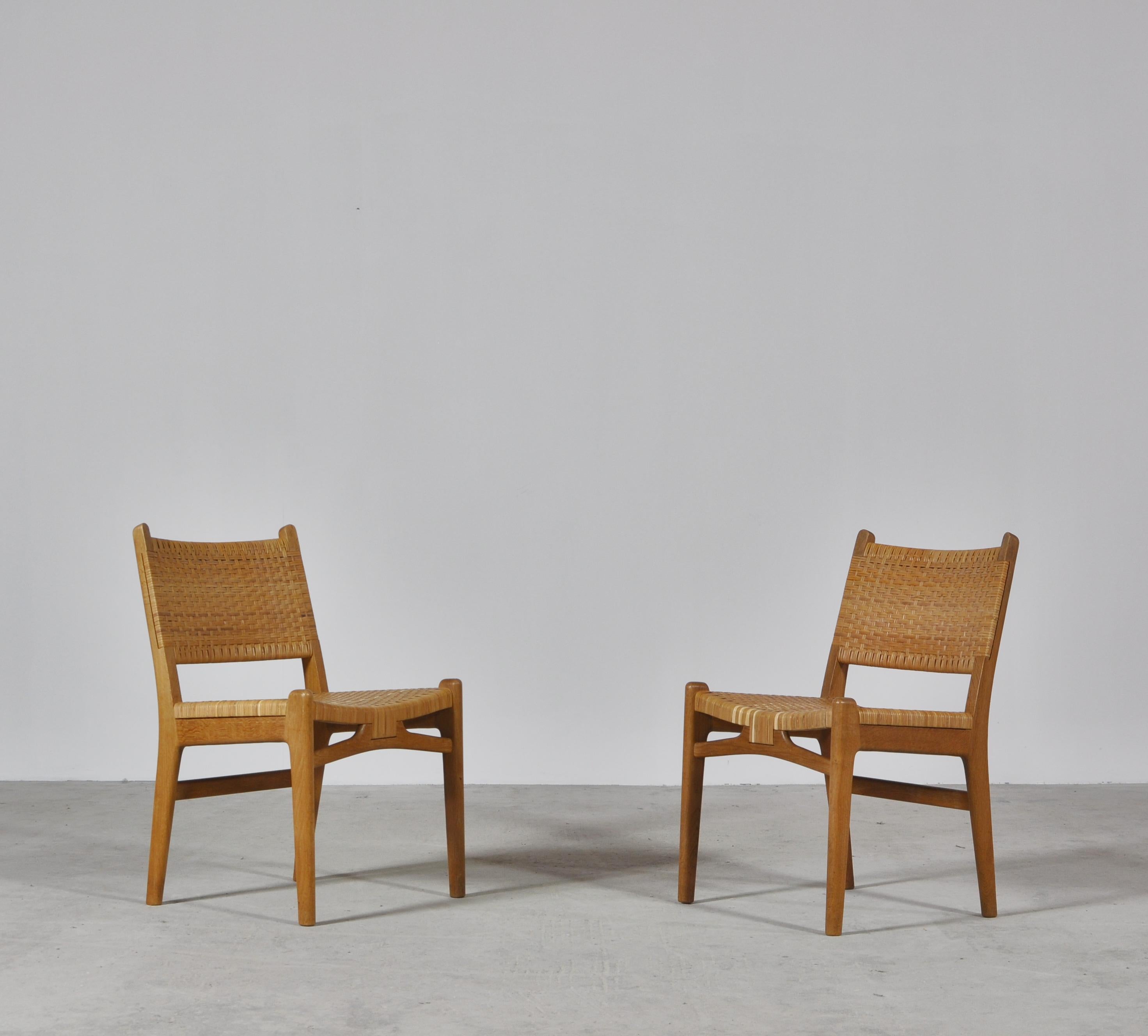 Great pair of side chairs by Hans J. Wegner made for Carl Hansen & Sons in the 1950s. Solid oak with beautiful grain and patina and rattan cane on the seats and back. This model is no longer being produced.