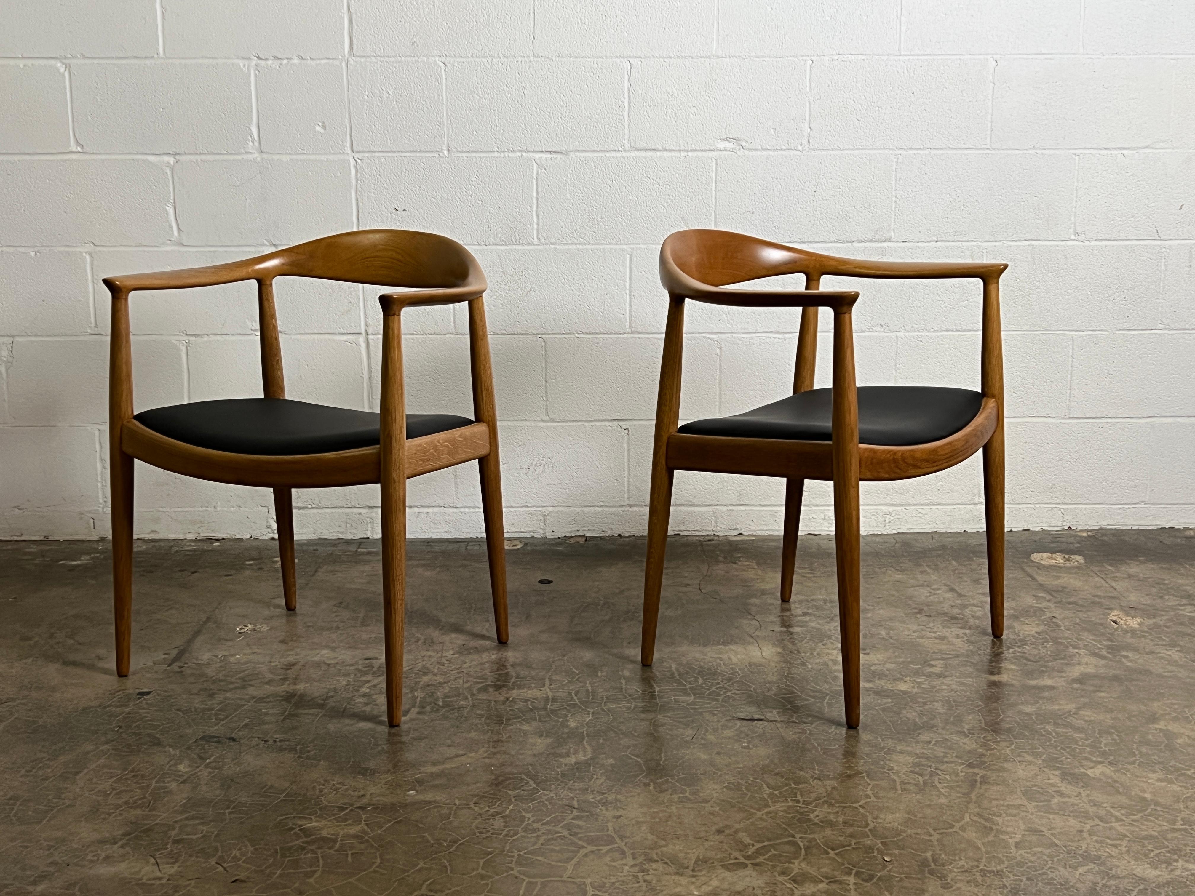 A pair of oak and leather round chairs designed by Hans Wegner for Johannes Hansen.