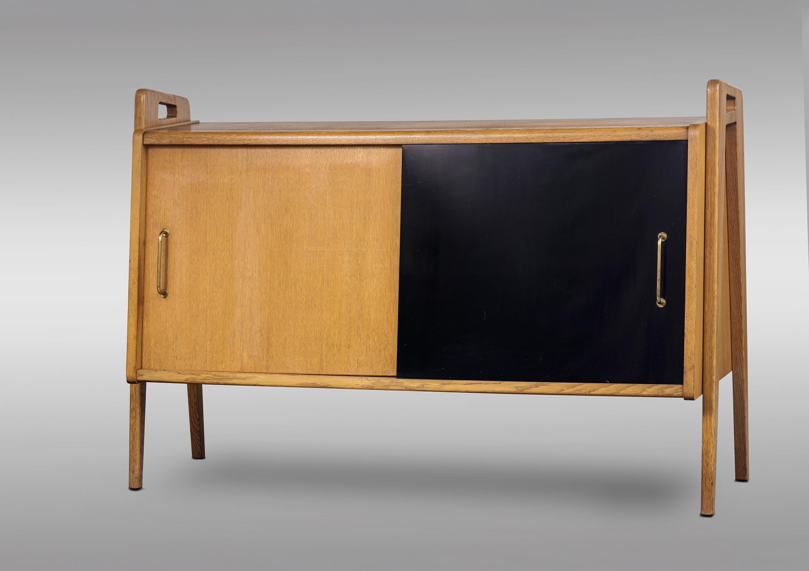 Pair of oak sideboards with sloping front, sliding doors, one of them lacquered in black. Interior with shelves. 
France 
Mid-20th