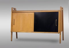 Pair of oak sideboards with sloping front, sliding doors, one of them lacquered