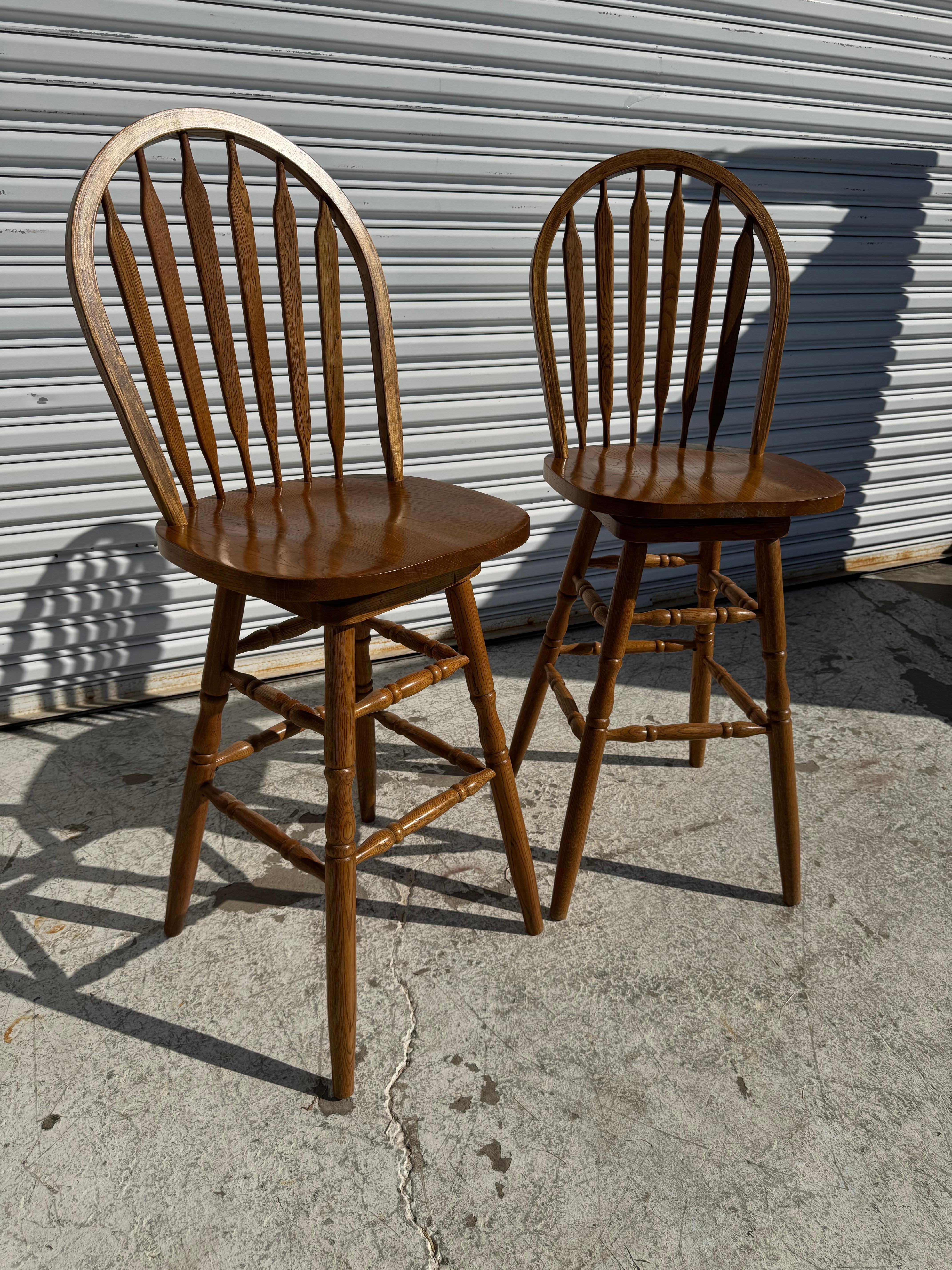 This pair of barstools are made of oak.
They're designed in the Windsor back fashion.
They swivel and have dual leveled foot rest.